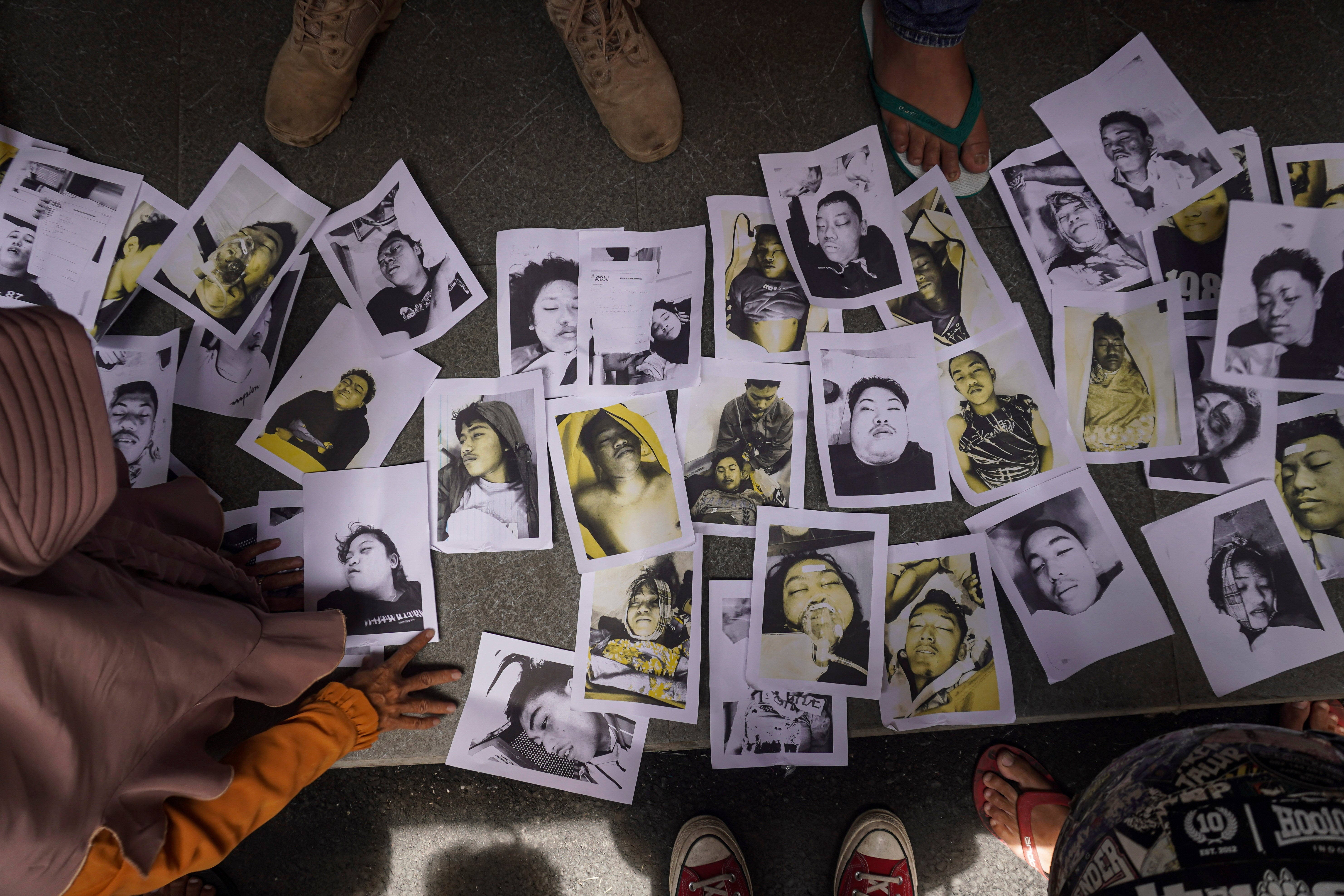 People looking for their relatives inspect photographs of football riot victims provided by volunteers to help them identify their family members in Malang