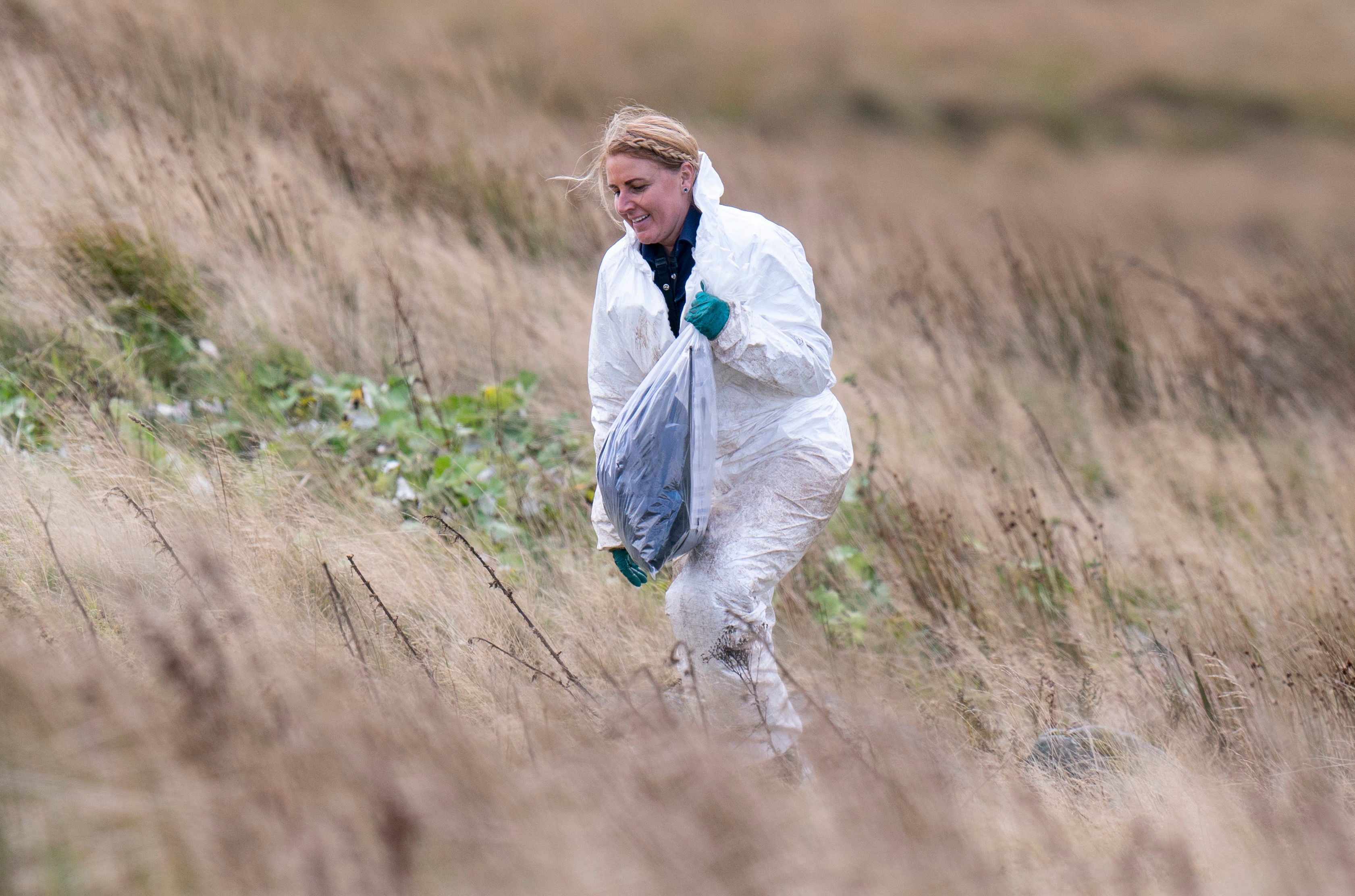 An officer carries an evidence bag on Saddleworth Moor