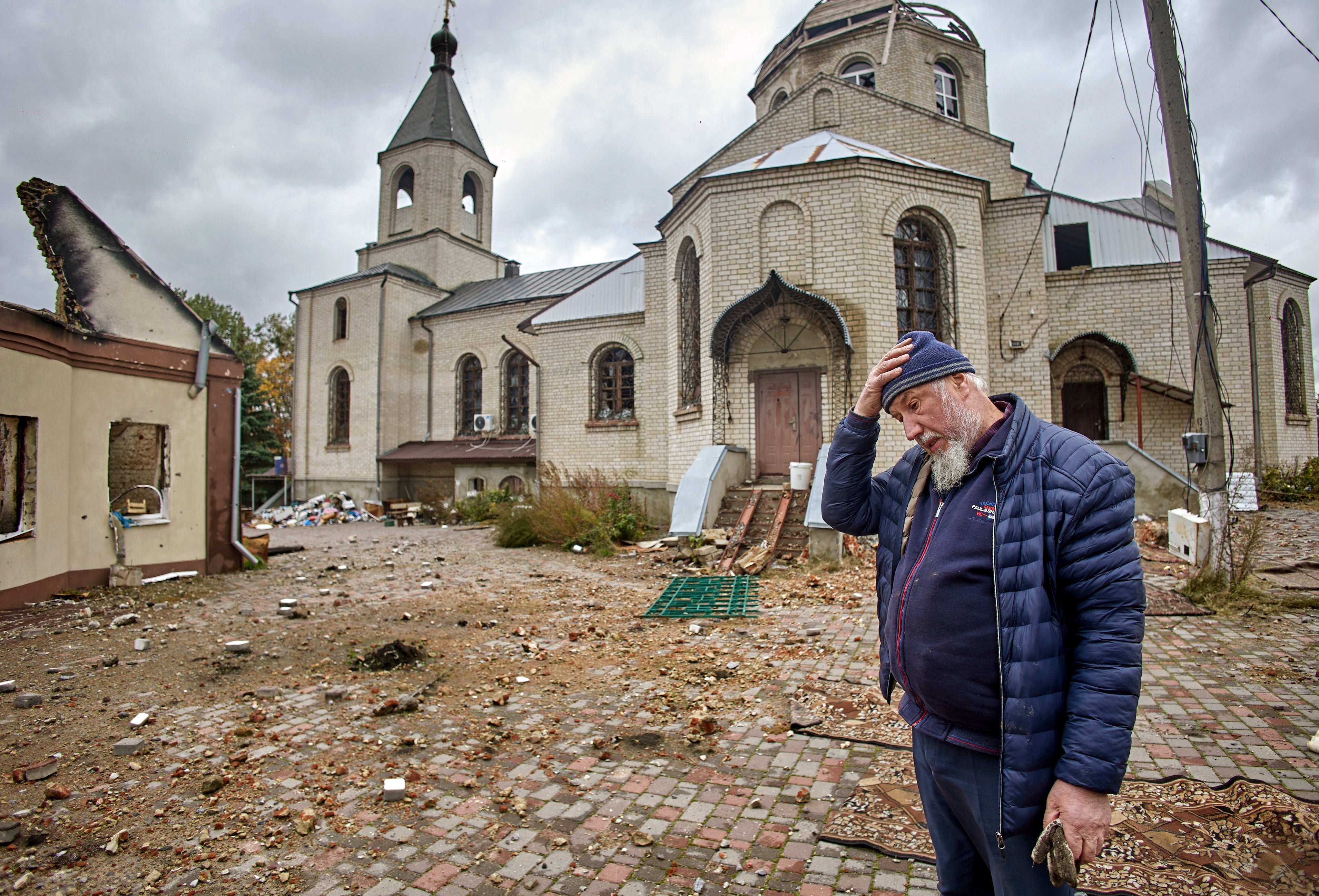 A priest walks past a damaged church in Ruska Lozova village in Kharkiv