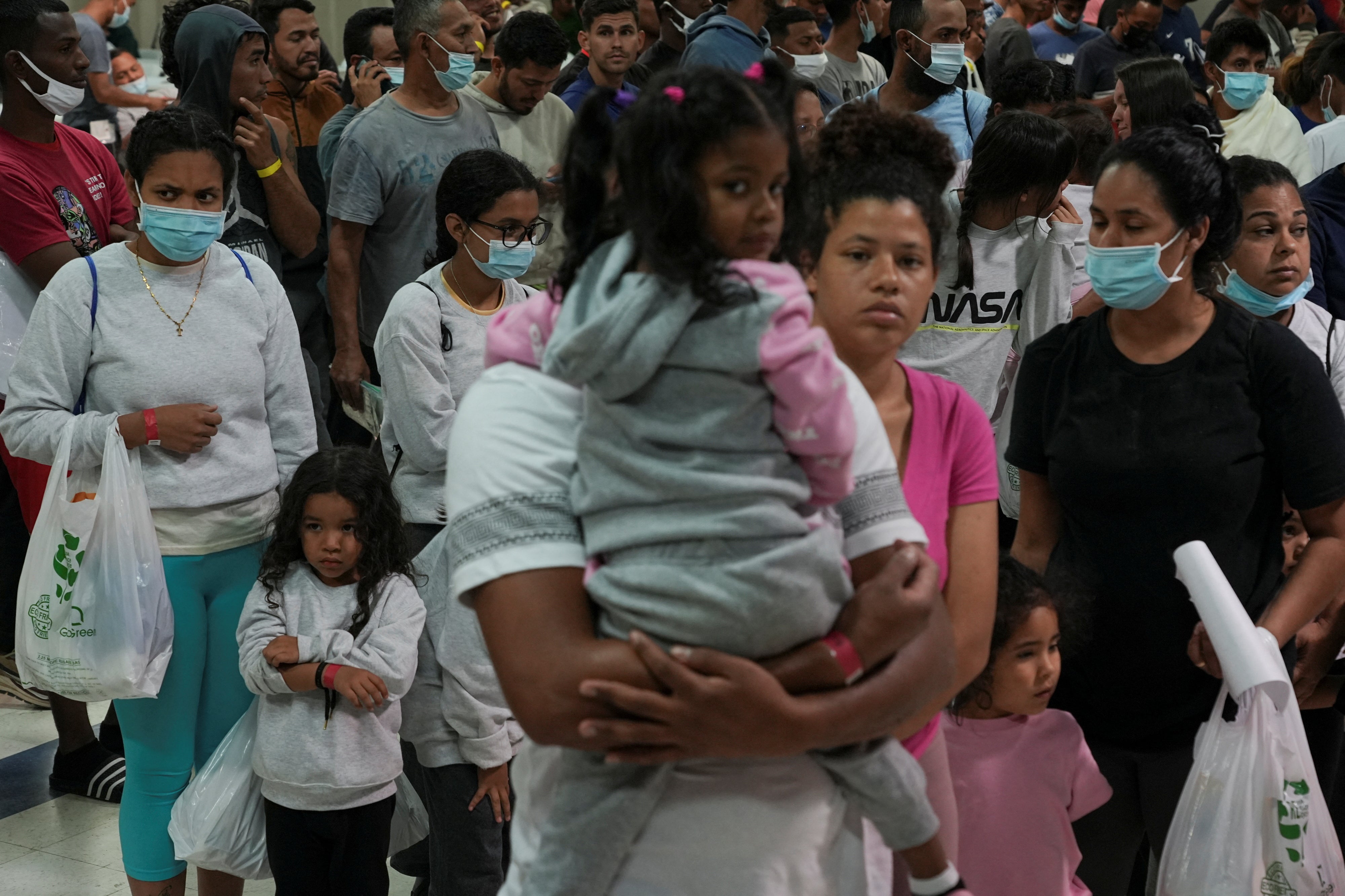 People seeking asylum in the US wait in line before boarding buses to New York and Chicago from El Paso, Texas on 3 October