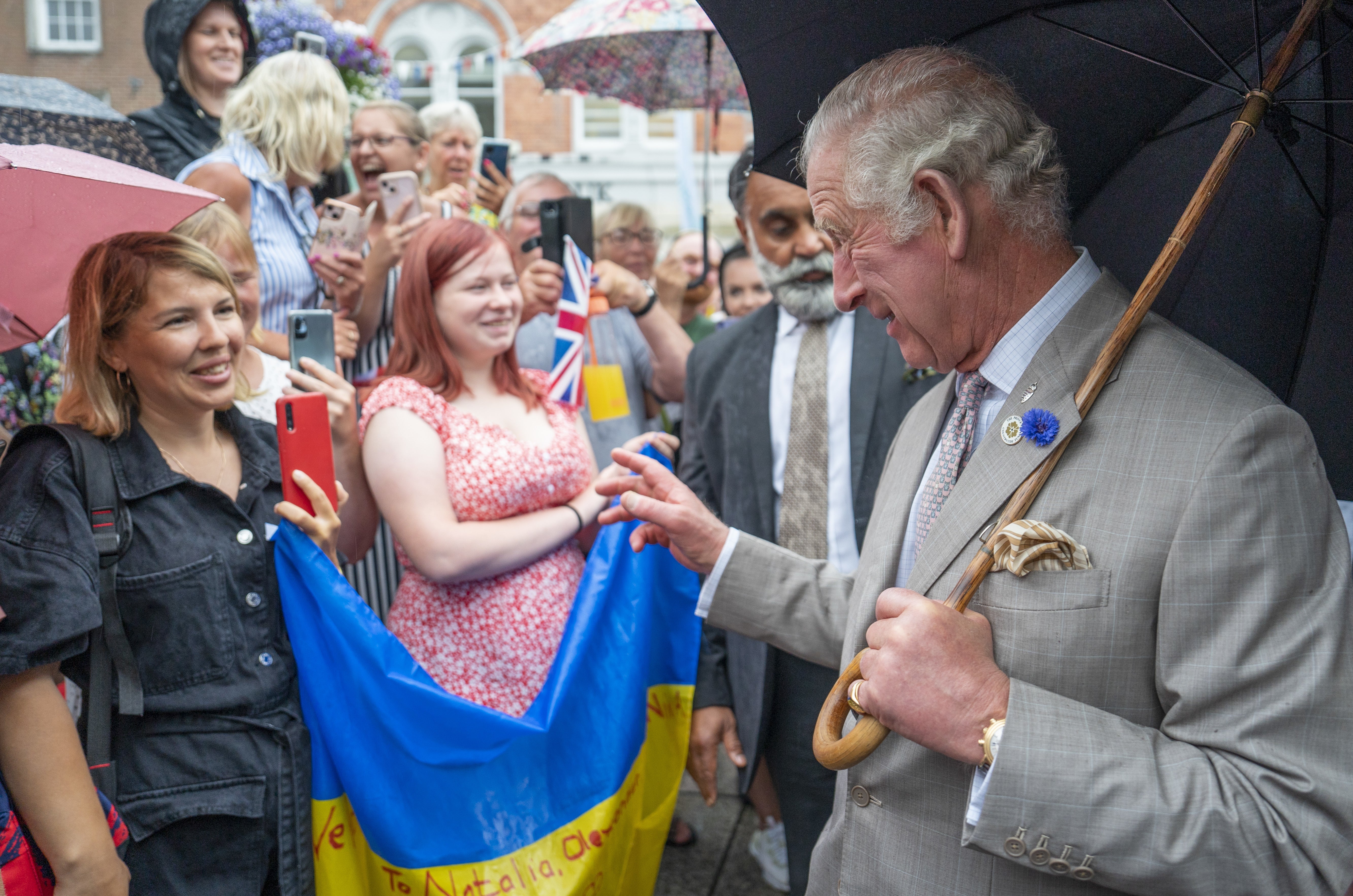 King Charles speaks to Ukrainian refugees with their national flag during a visit to Launceston in Cornwall