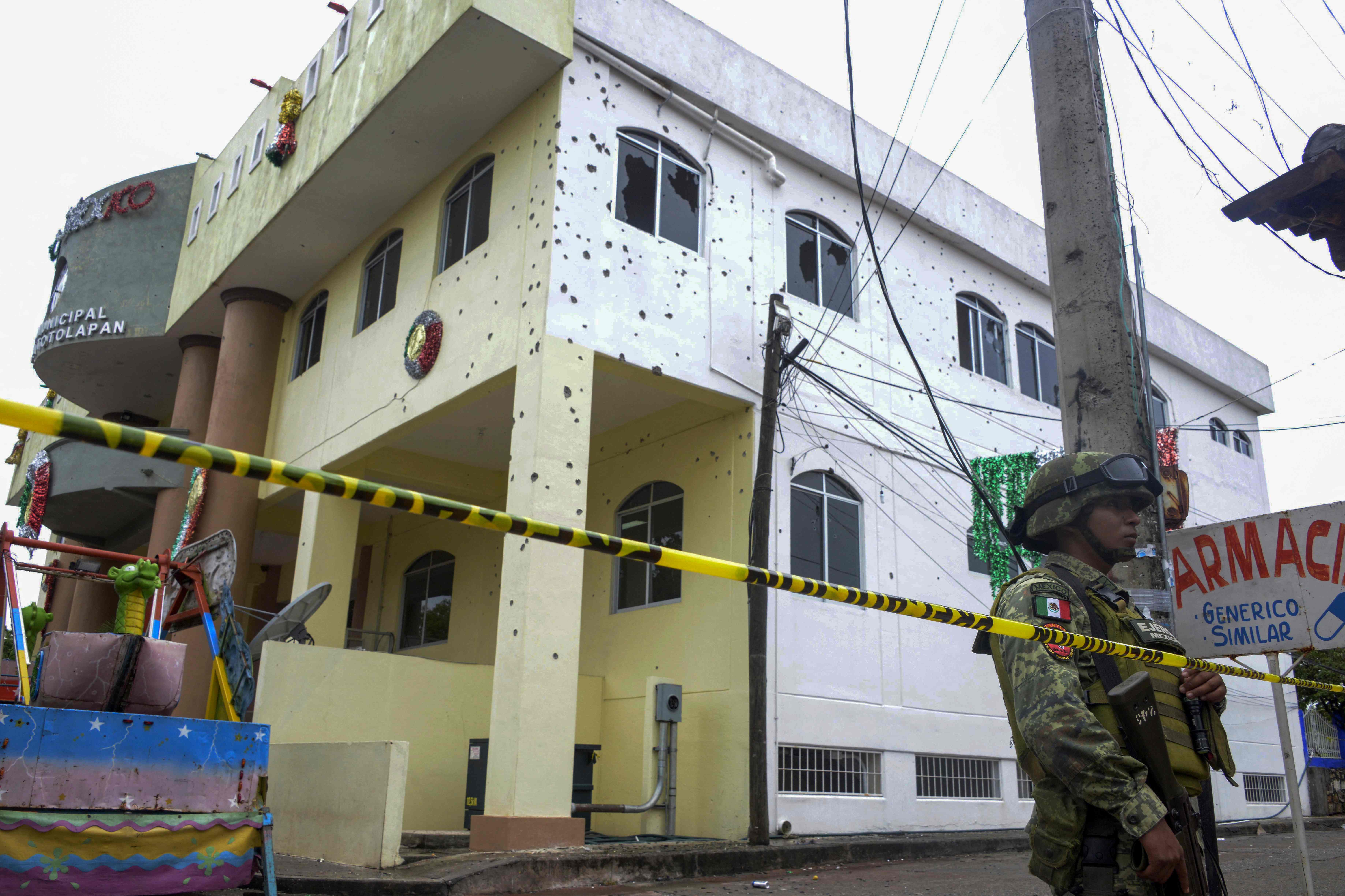 A member of the Mexican Army stands guard in front of the bullet-ridden building of the Municipality of San Miguel Totolapan, state of Guerrero, Mexico, on October 2022