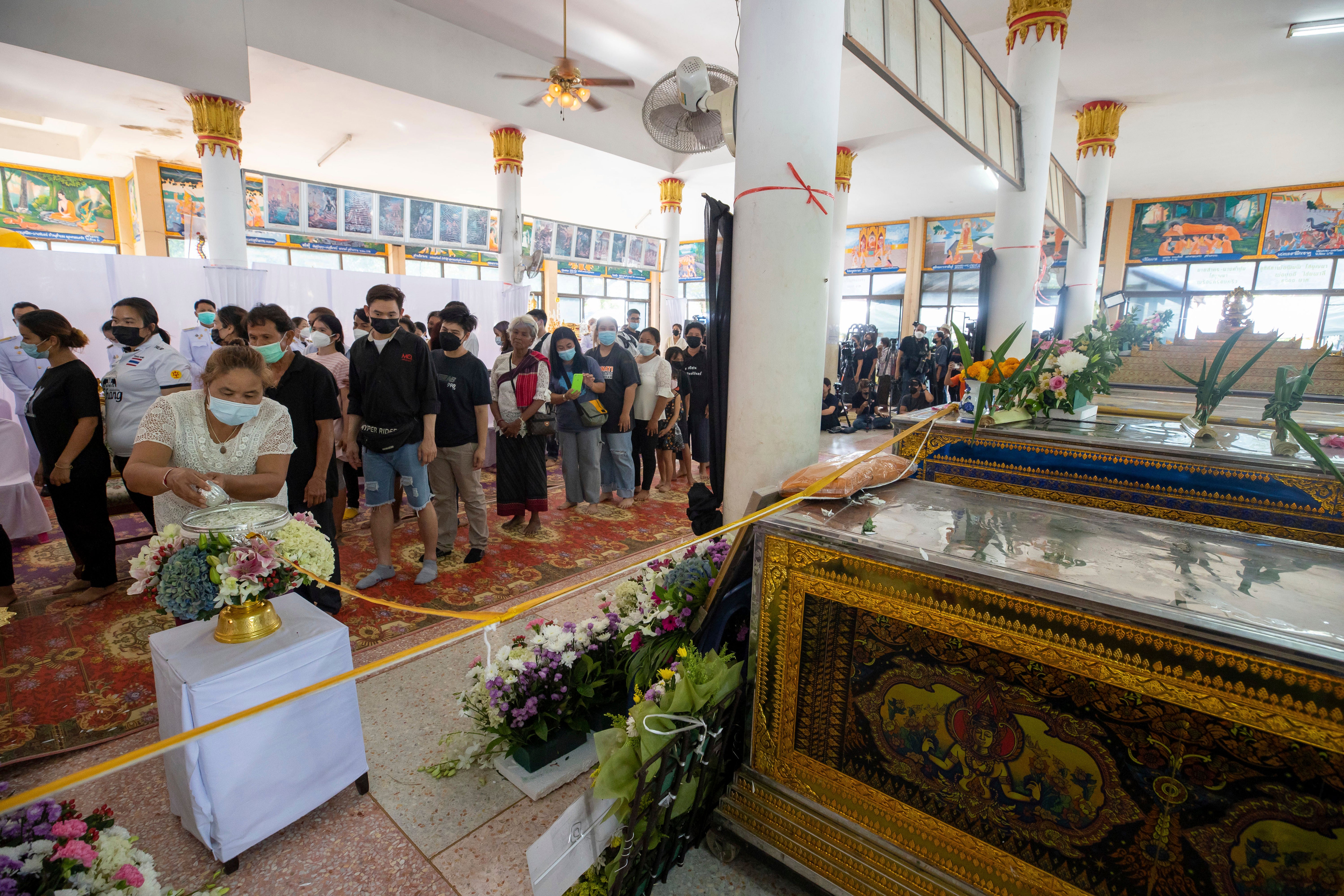 Villagers pour water in front of coffins during the Buddhist washing ritual for the victims