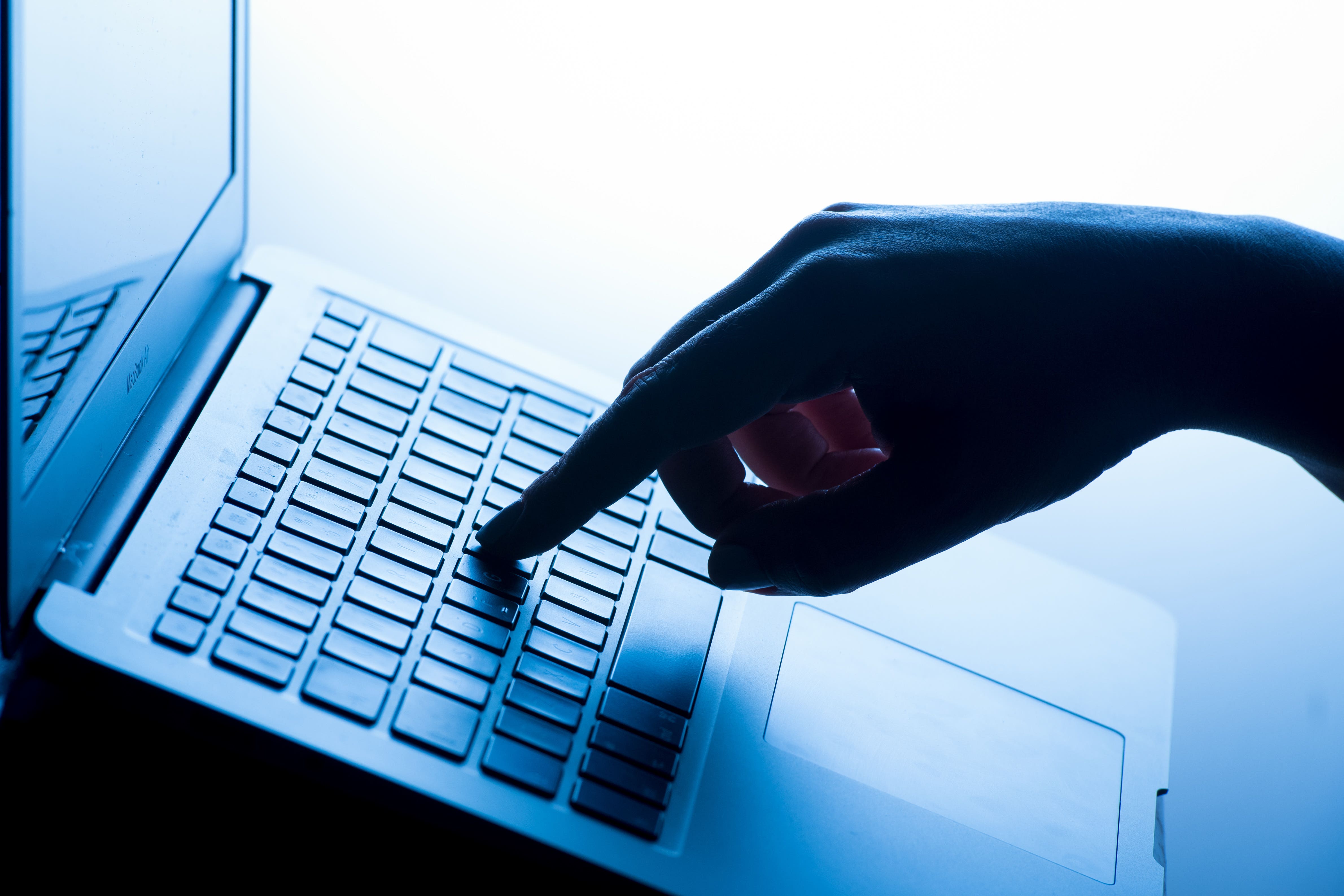 A woman’s hand presses a key of a laptop keyboard.
