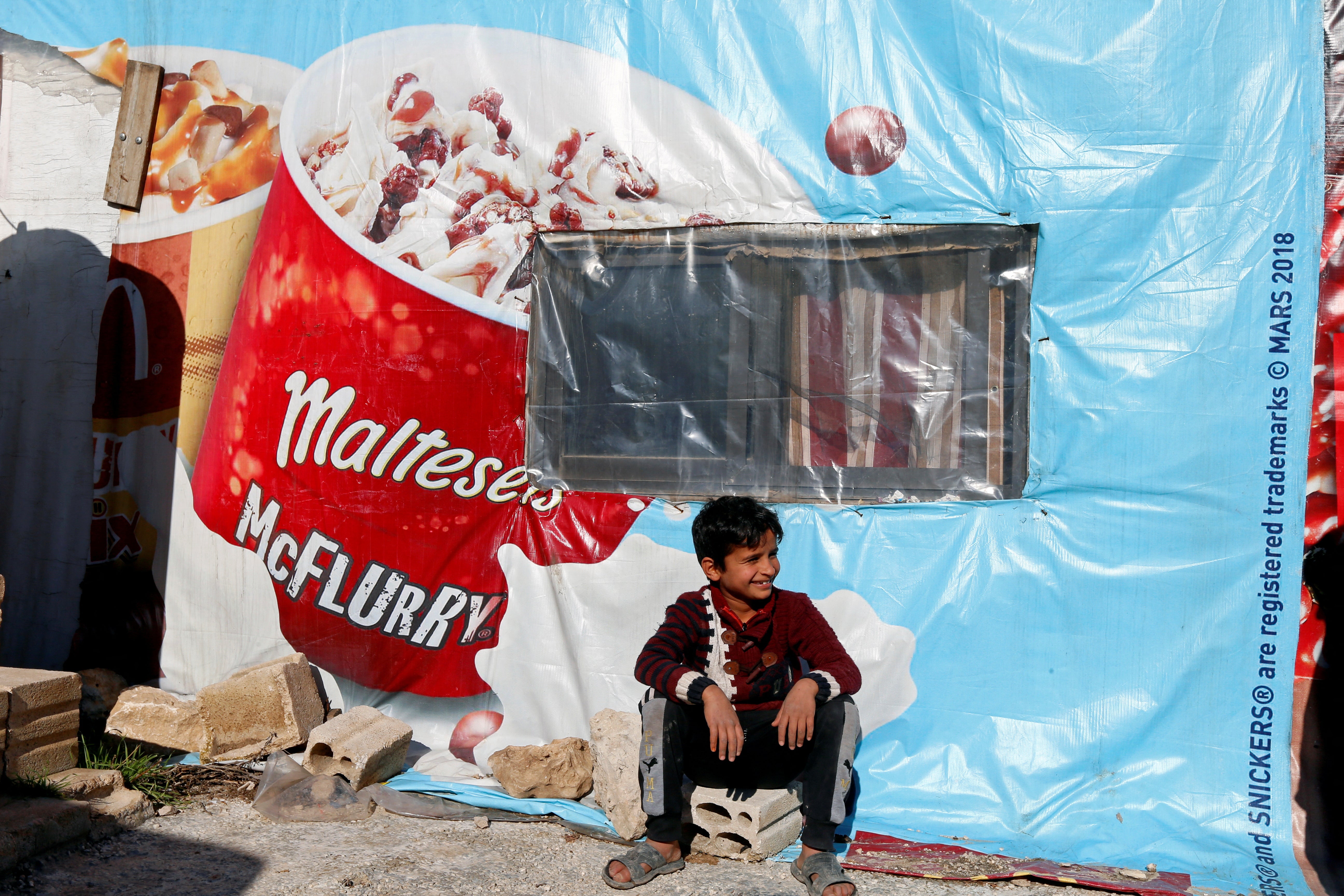 A Syrian refugee boy sits outside a tent at a camp in Bar Elias, in the Bekaa Valley, Lebanon