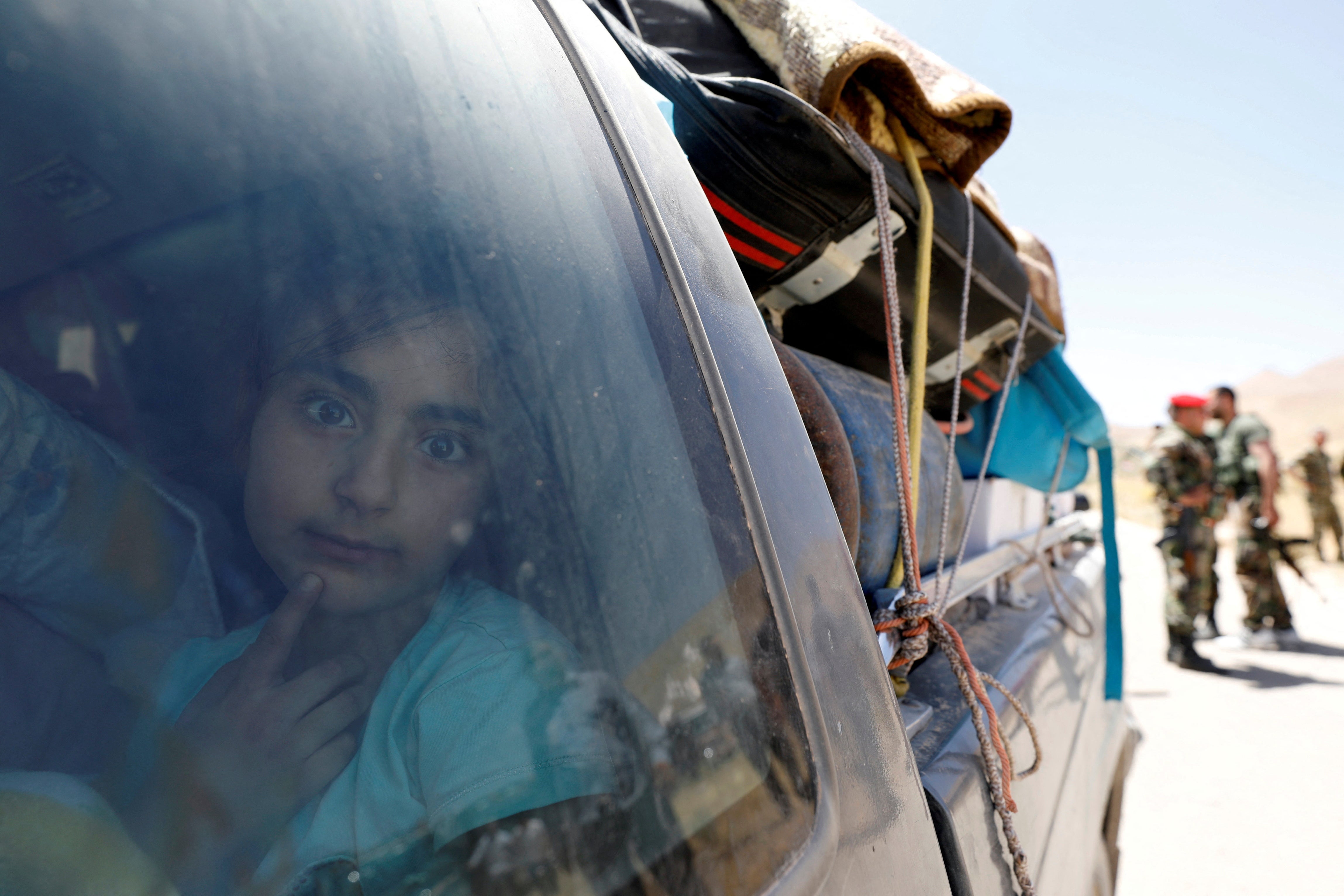 A Syrian refugee girl who left Lebanon looks through a window as she arrives in Qalamoun, Syria