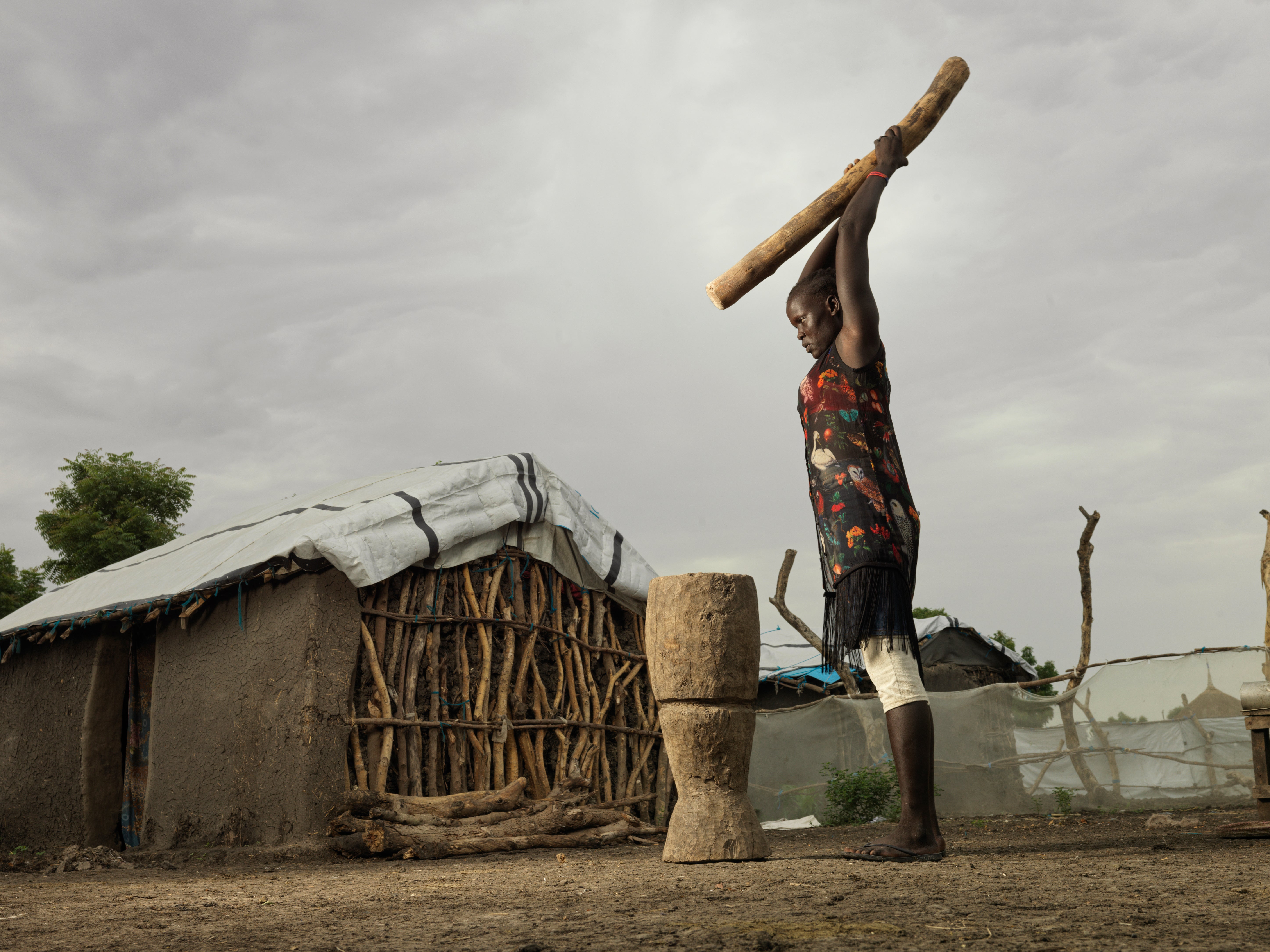 Nyakieth Kulang, 22, pounds the rice to remove the husk