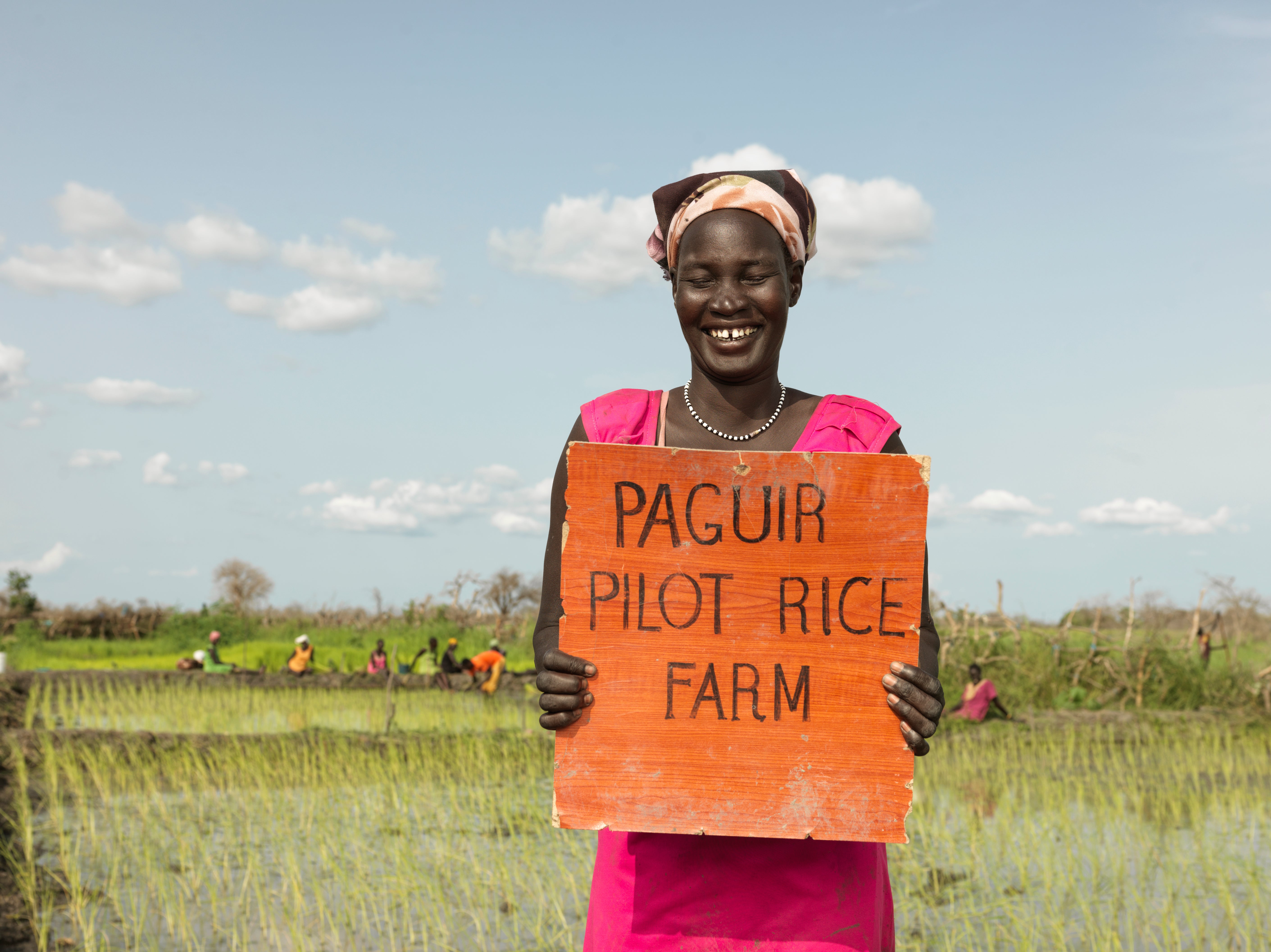 Nyaok Dieng,34, laughs while holding the rice paddy sign