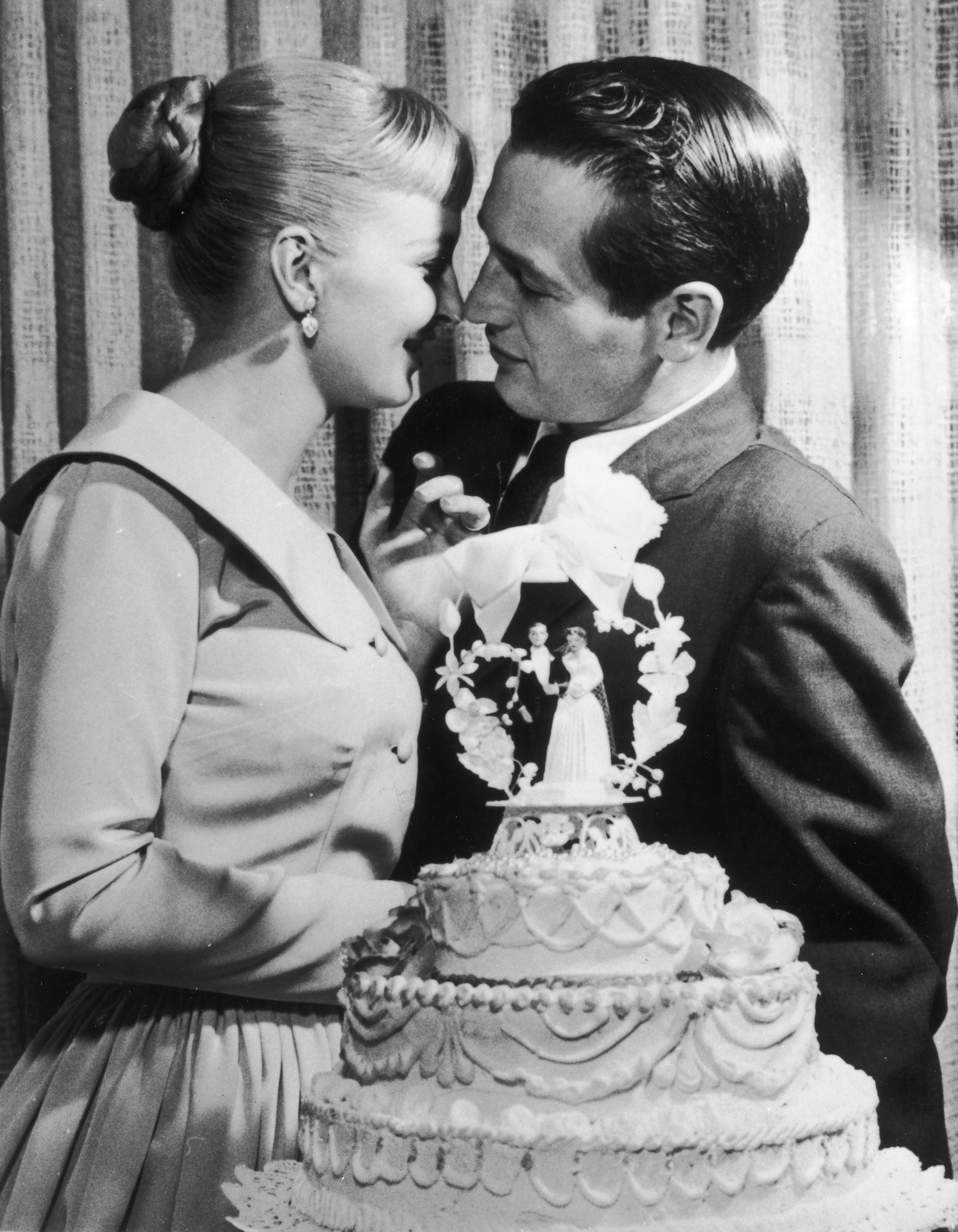 Paul Newman and Joanne Woodward kiss behind a wedding cake during their wedding reception at the El Rancho hotel-casino, Las Vegas