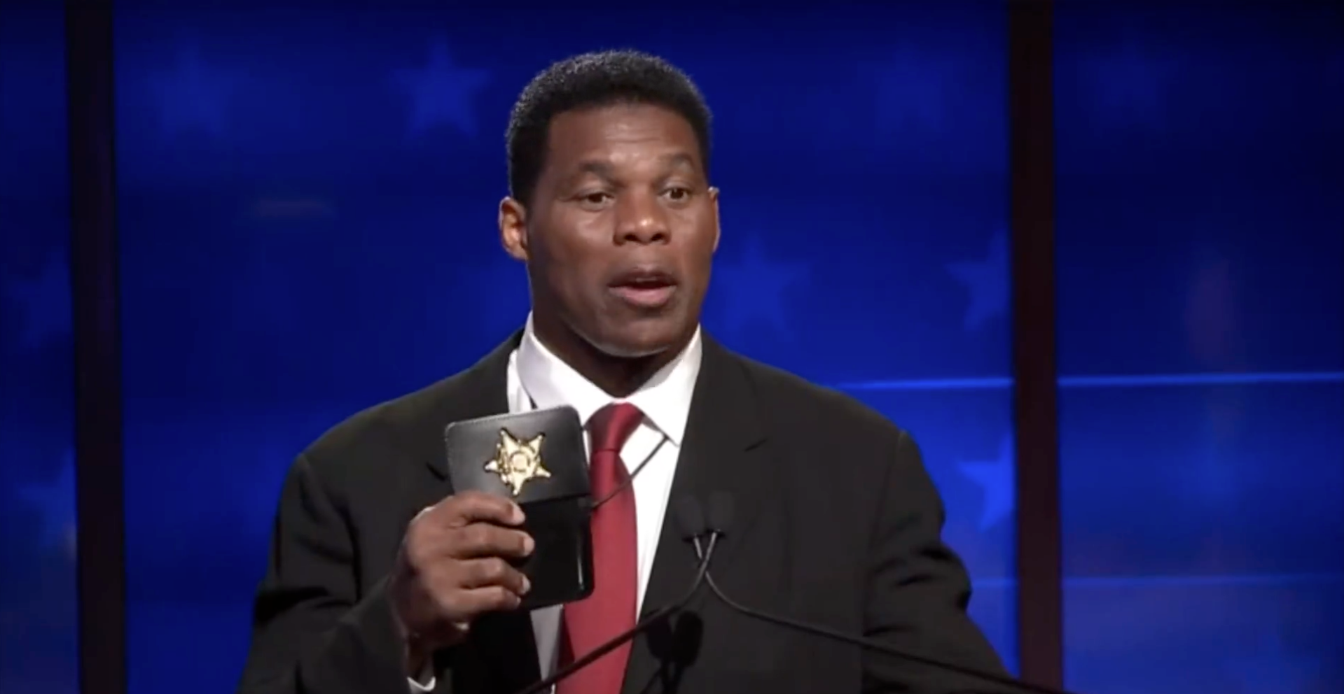 Georgia Republican Senate nominee Herschel Walker holds up a prop police badge during debate against Democratic Senator Rapahel Warnock