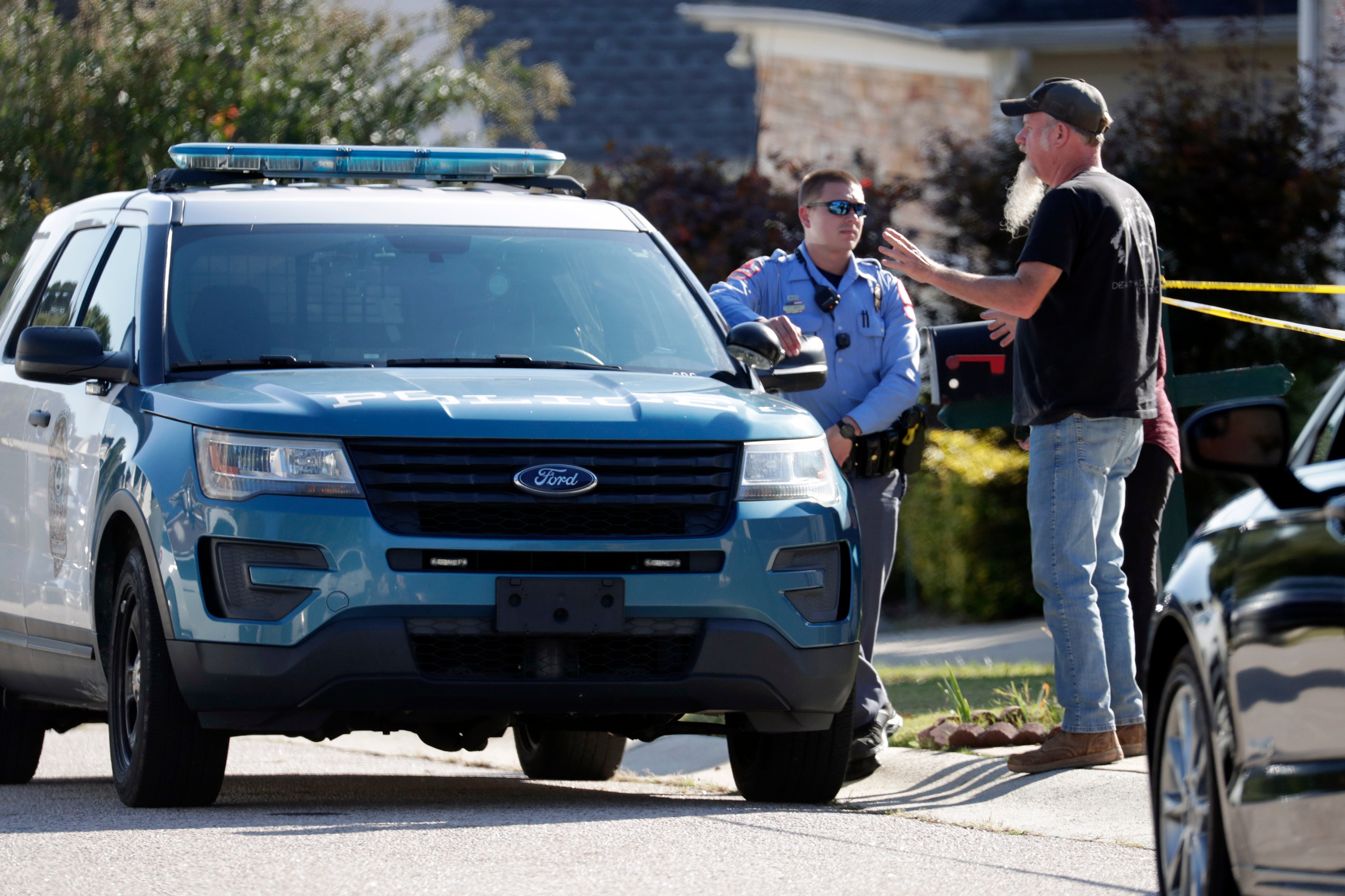 Residents talk with a police officer in front of the house where the suspected shooter lived on Sahalee Way following a shooting in Raleigh, N.C., Friday, Oct. 14, 2022