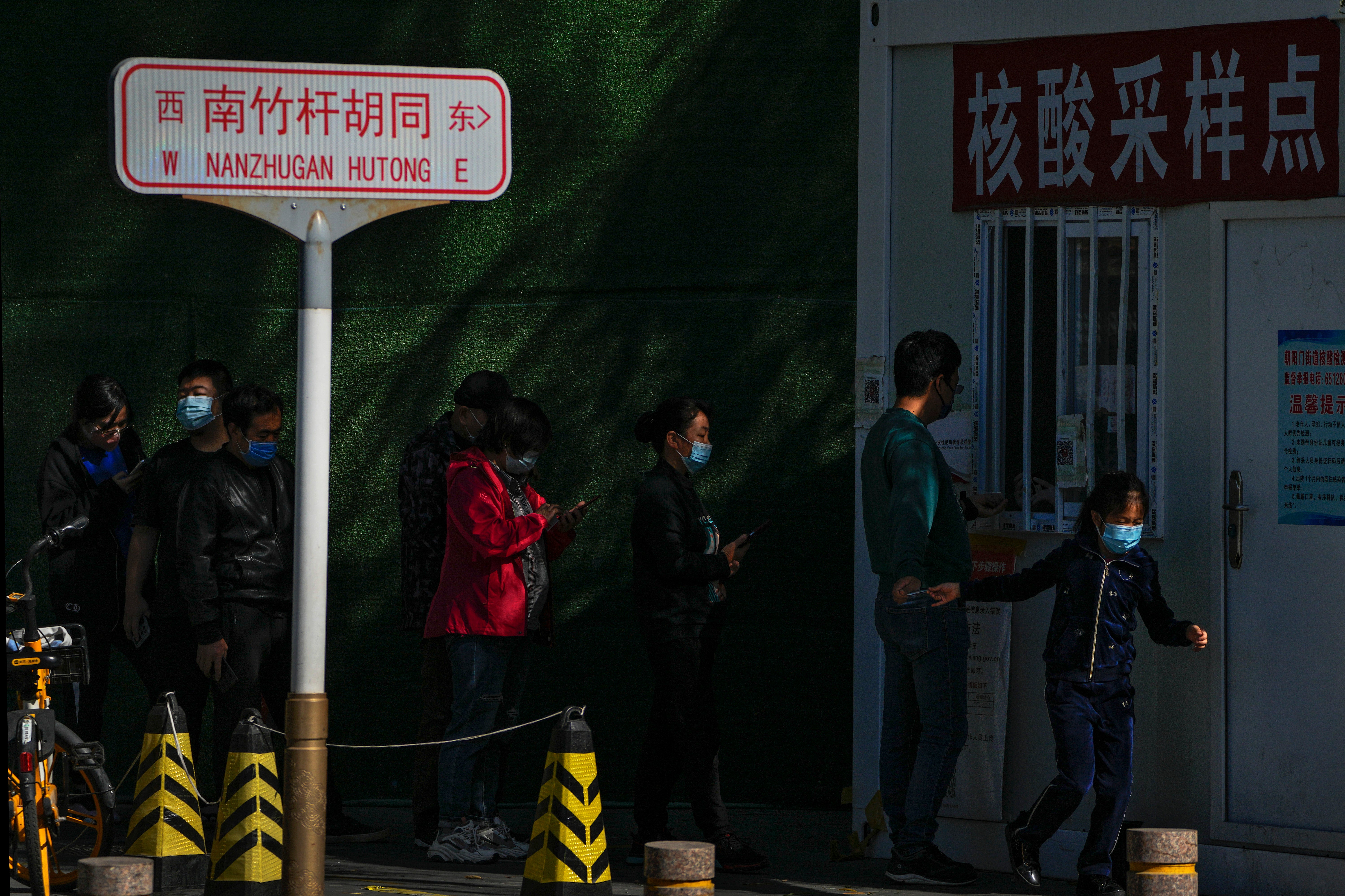 Residents wearing face masks line up to get their routine Covid-19 throat swabs at a coronavirus testing site