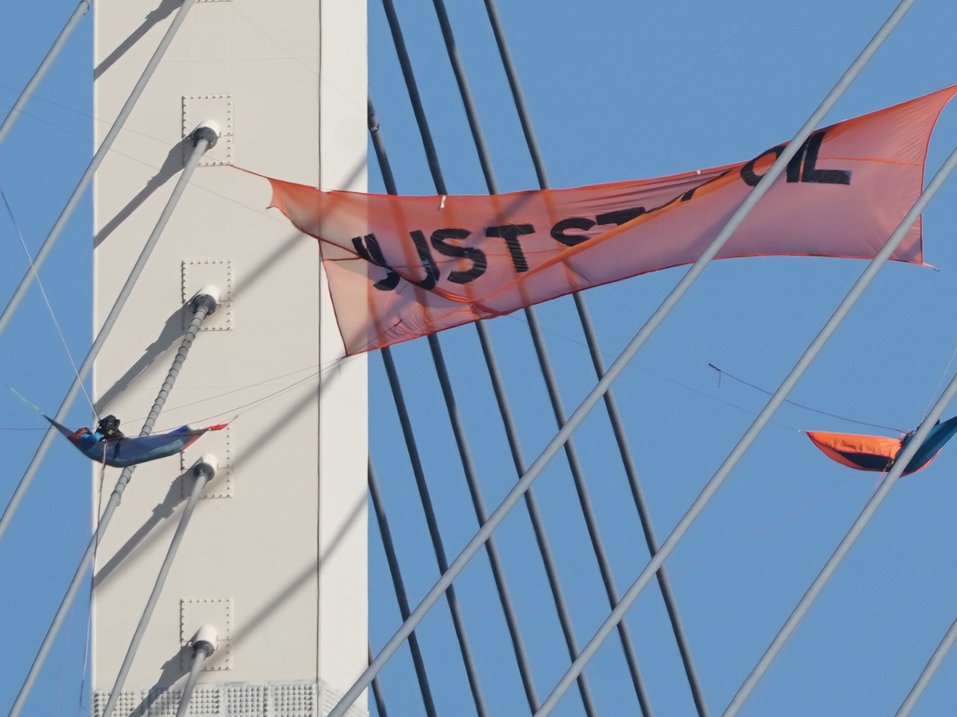 A Just Stop Oil protester hangs from the bridge