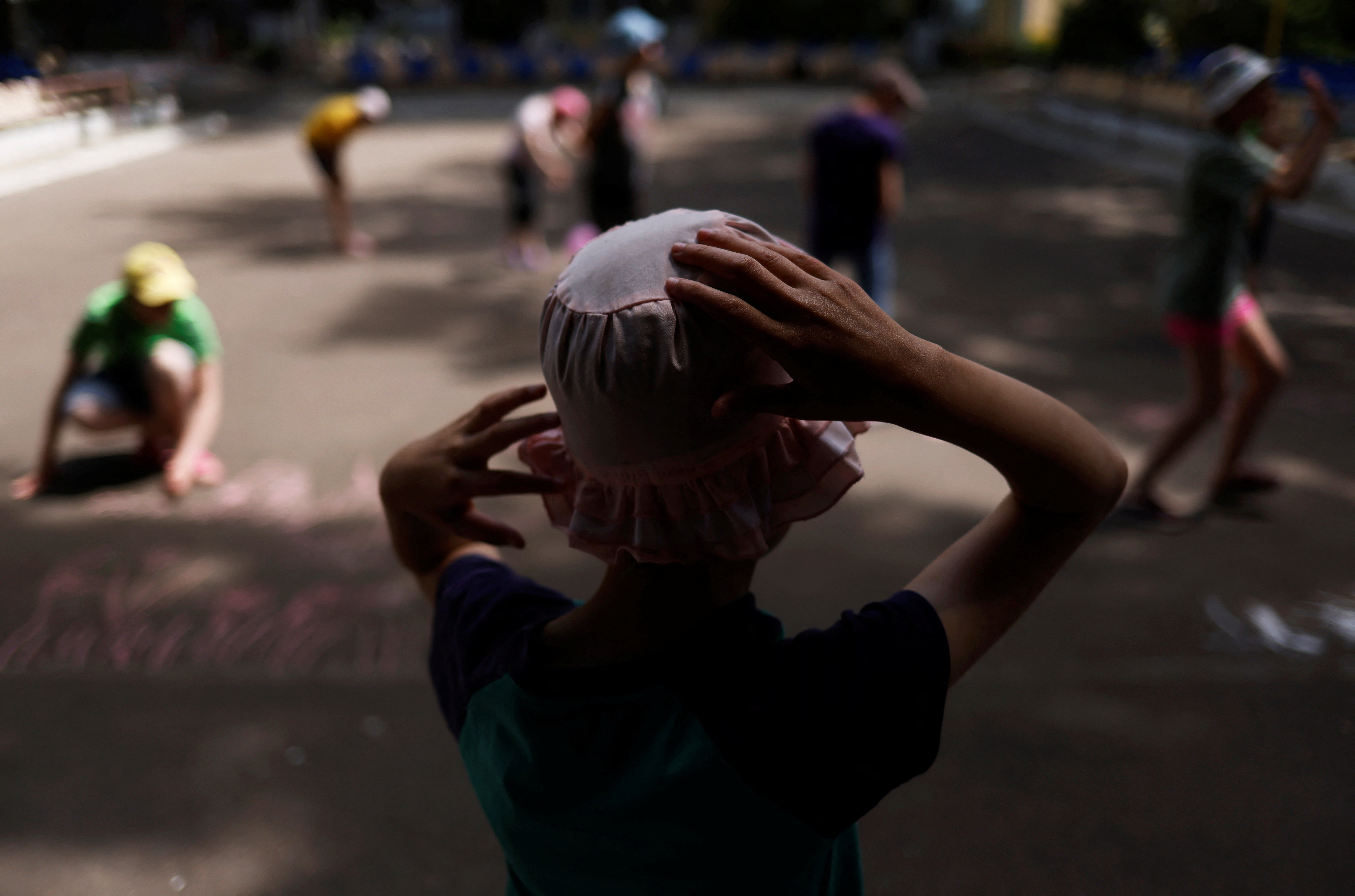 Tanya, 12, who is autistic and does not speak, watches other children draw with chalk in a play area at a facility for people with special needs in Odesa, Ukraine