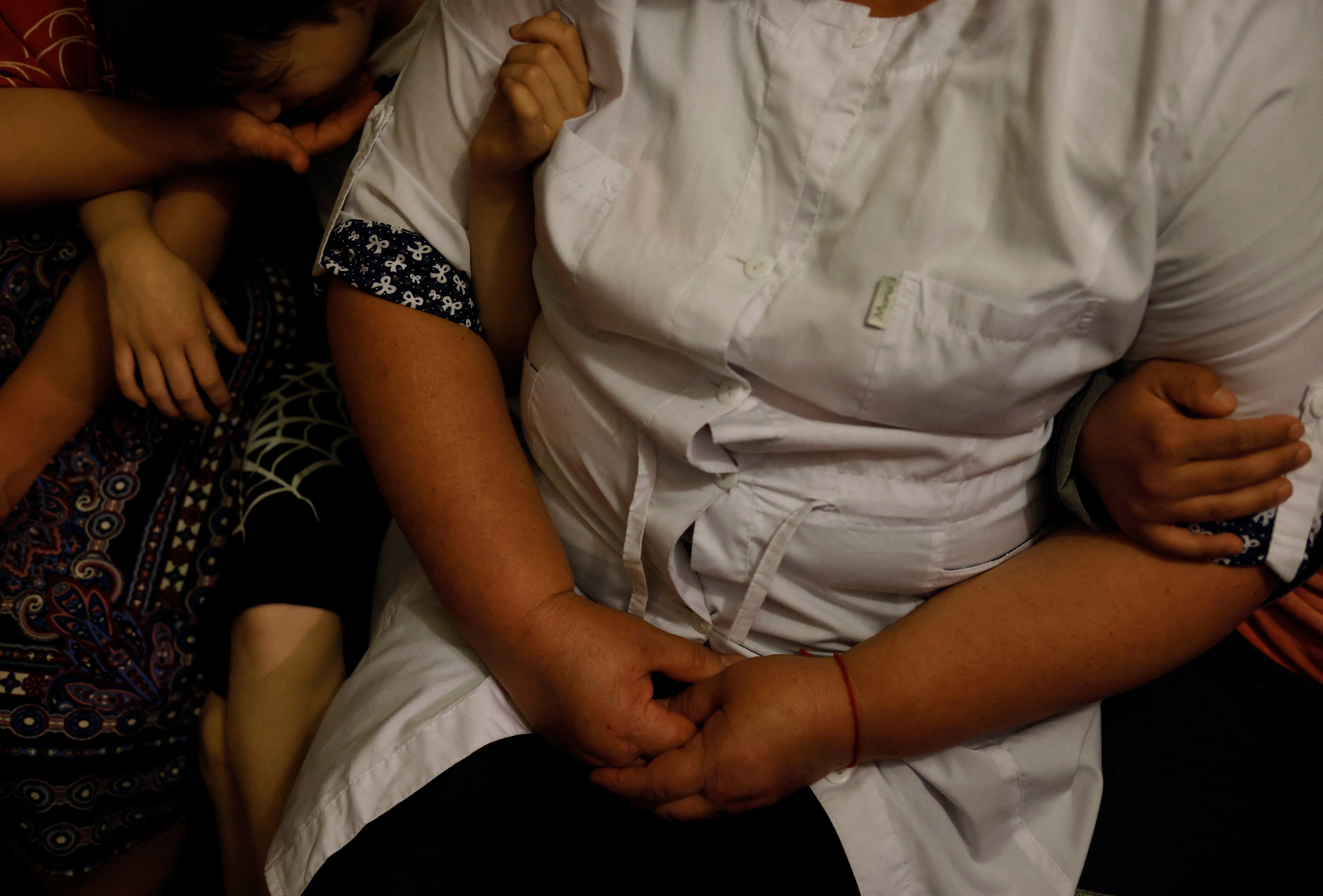 Nurse Rita Barba, 52, sits with children in the shelter