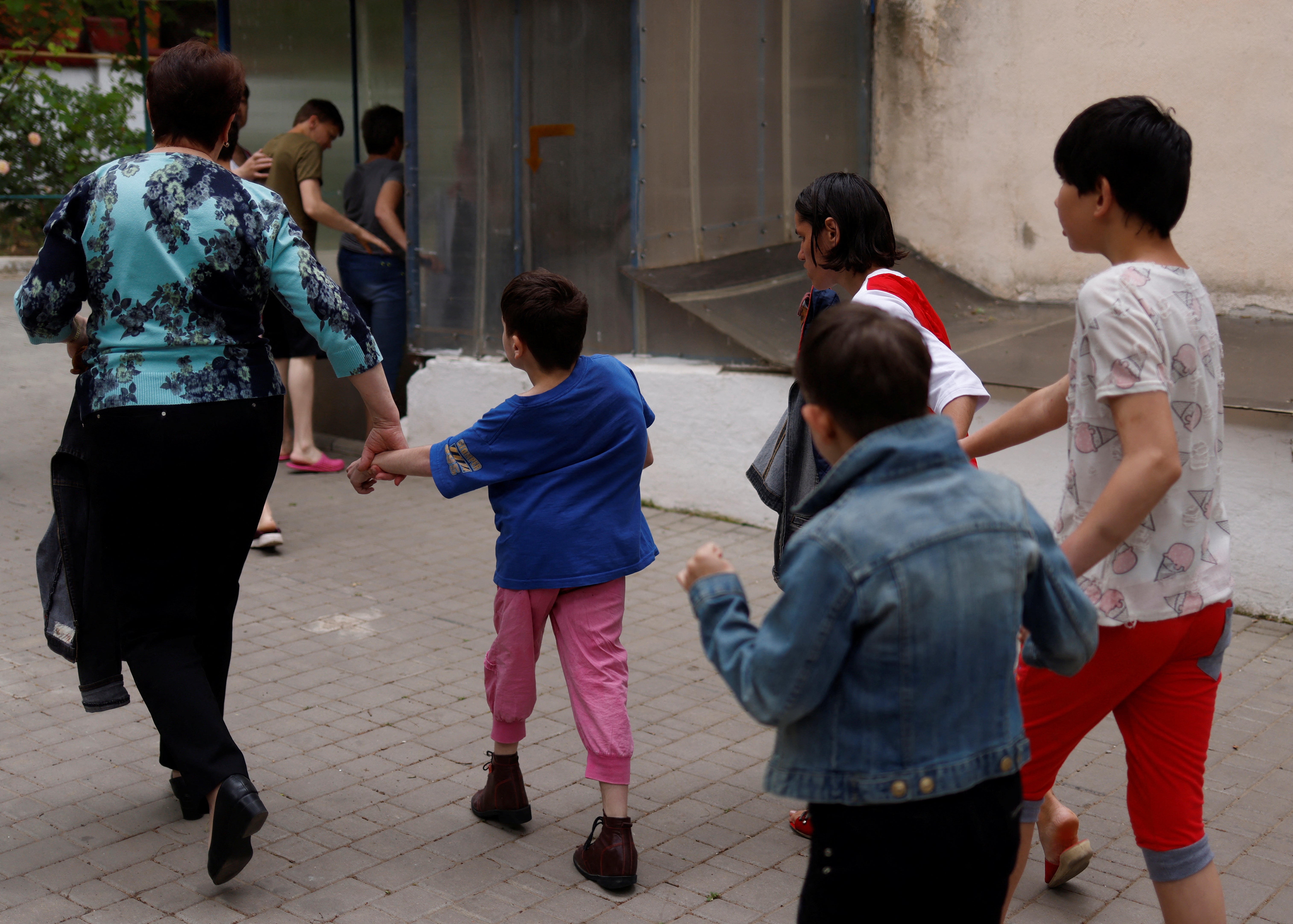 Teacher Irina Nikolaeva Ogurtsova leads children to a basement shelter as an air raid warning goes off at the facility