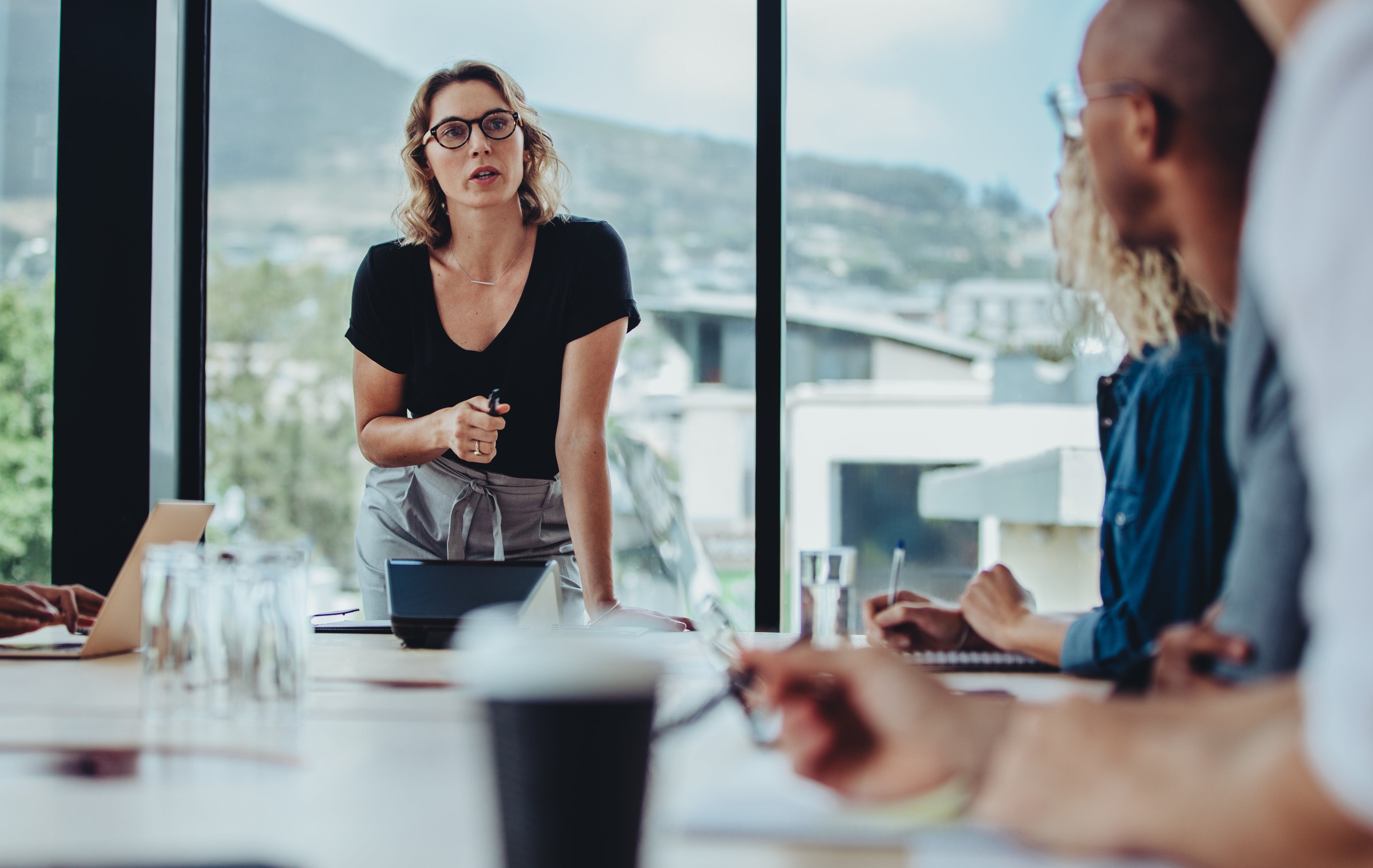 Businesswoman addressing a boardroom meeting with colleagues sitting at table. Female manager addressing her team at a meeting