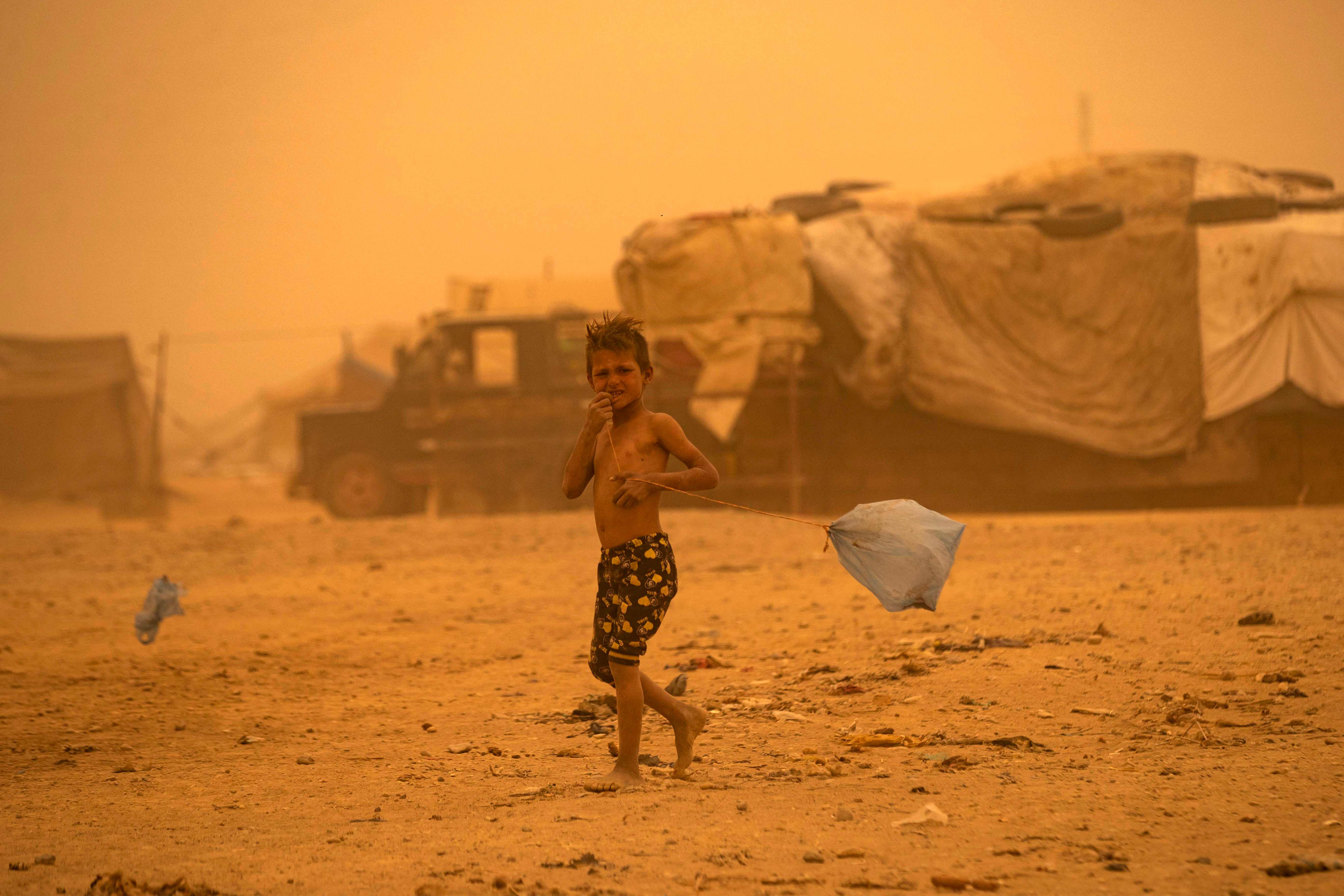 A boy walks amid a sandstorm at the Sahlah al-Banat camp for displaced people in the countryside of Raqa in northern Syria. Detention camps have been described as hellish and squalid by human rights groups