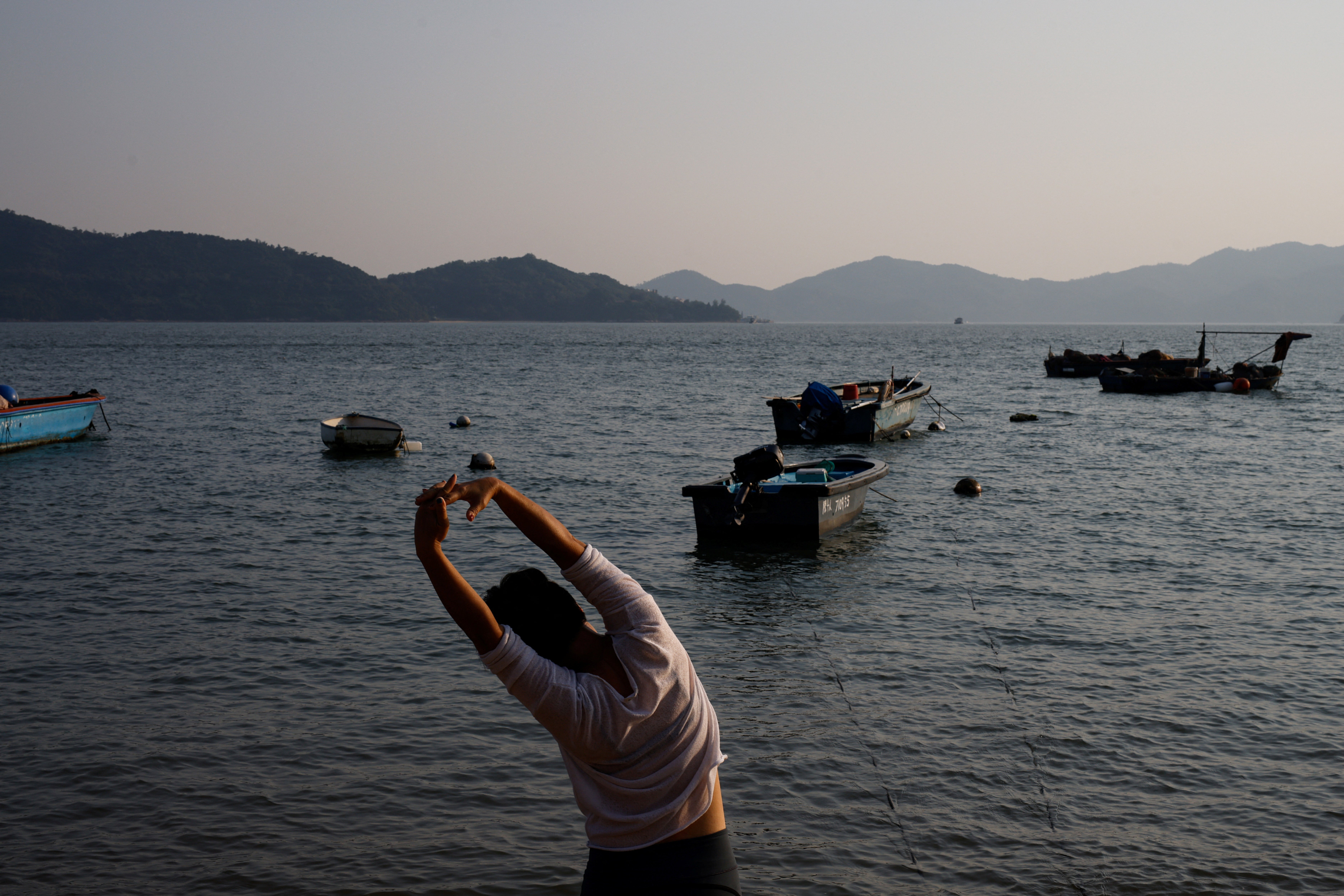 A woman stretches on the beach as she takes part in a meditation session