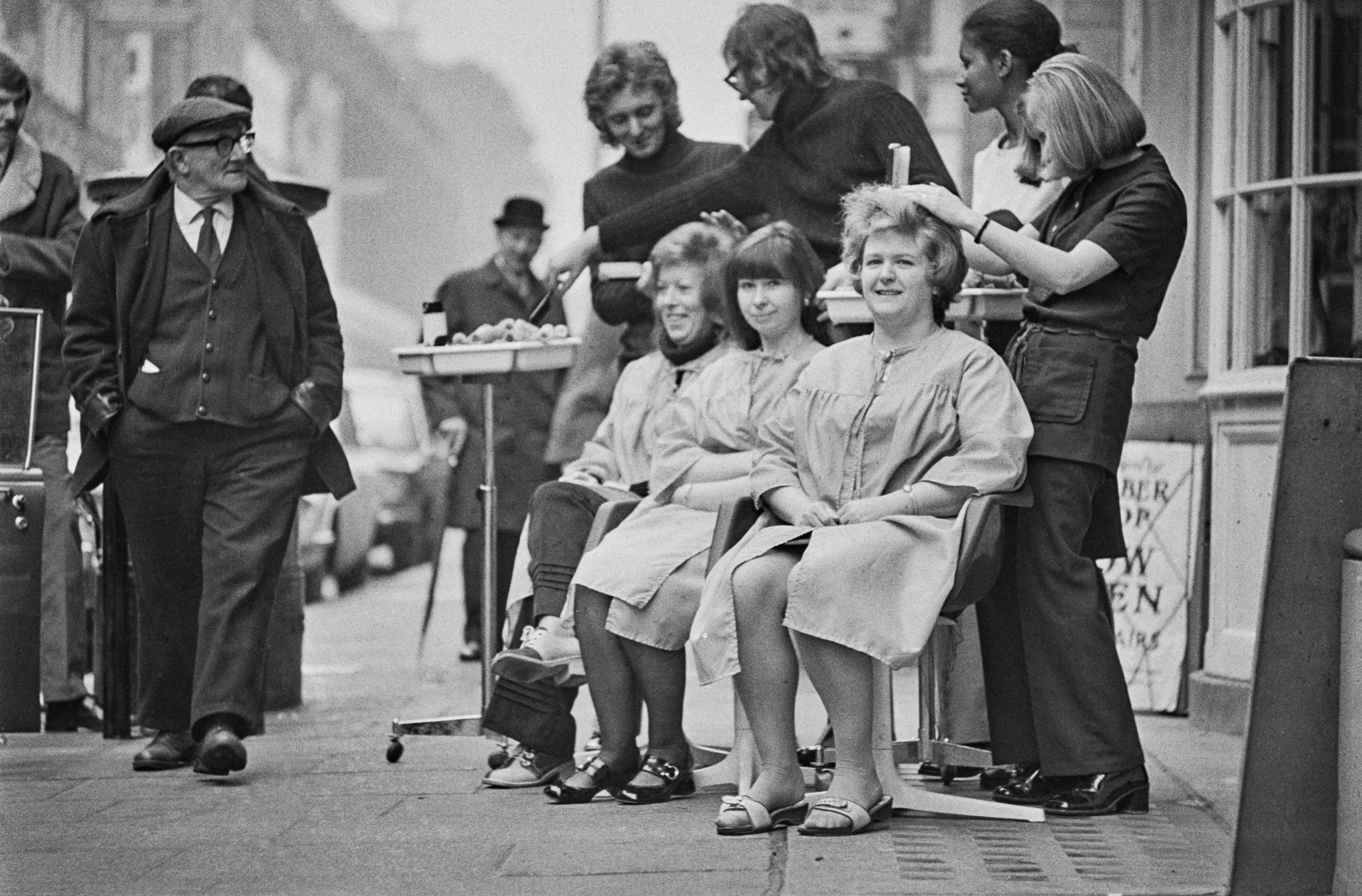 Customers having their hair cut on the pavement in Hatton Garden, London, due to power cuts following a miners' strike, UK, 17th February 1972