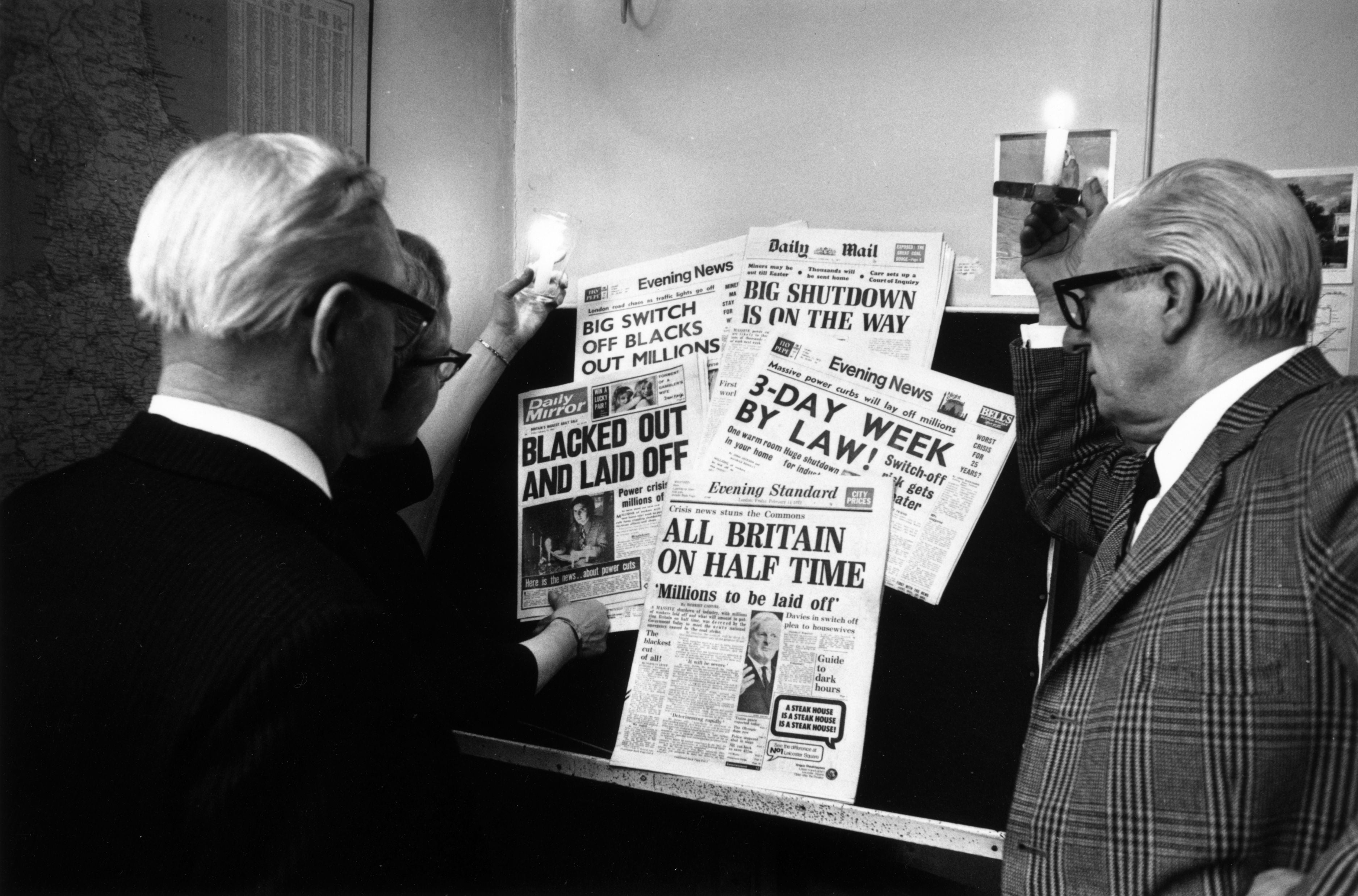 People in London using candles to read newspaper headlines about the continuing miners’ strike