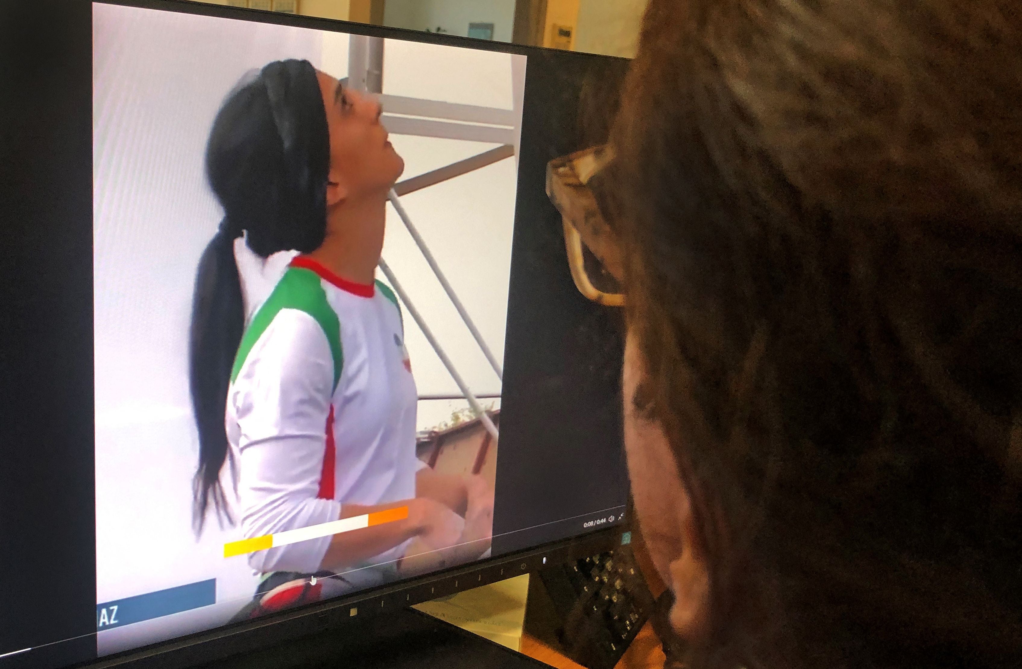 A woman looks at a screen displaying a video of an international climbing competition is Seoul, South Korea, during which Iranian climber Elnaz Rekabi competes without a hijab