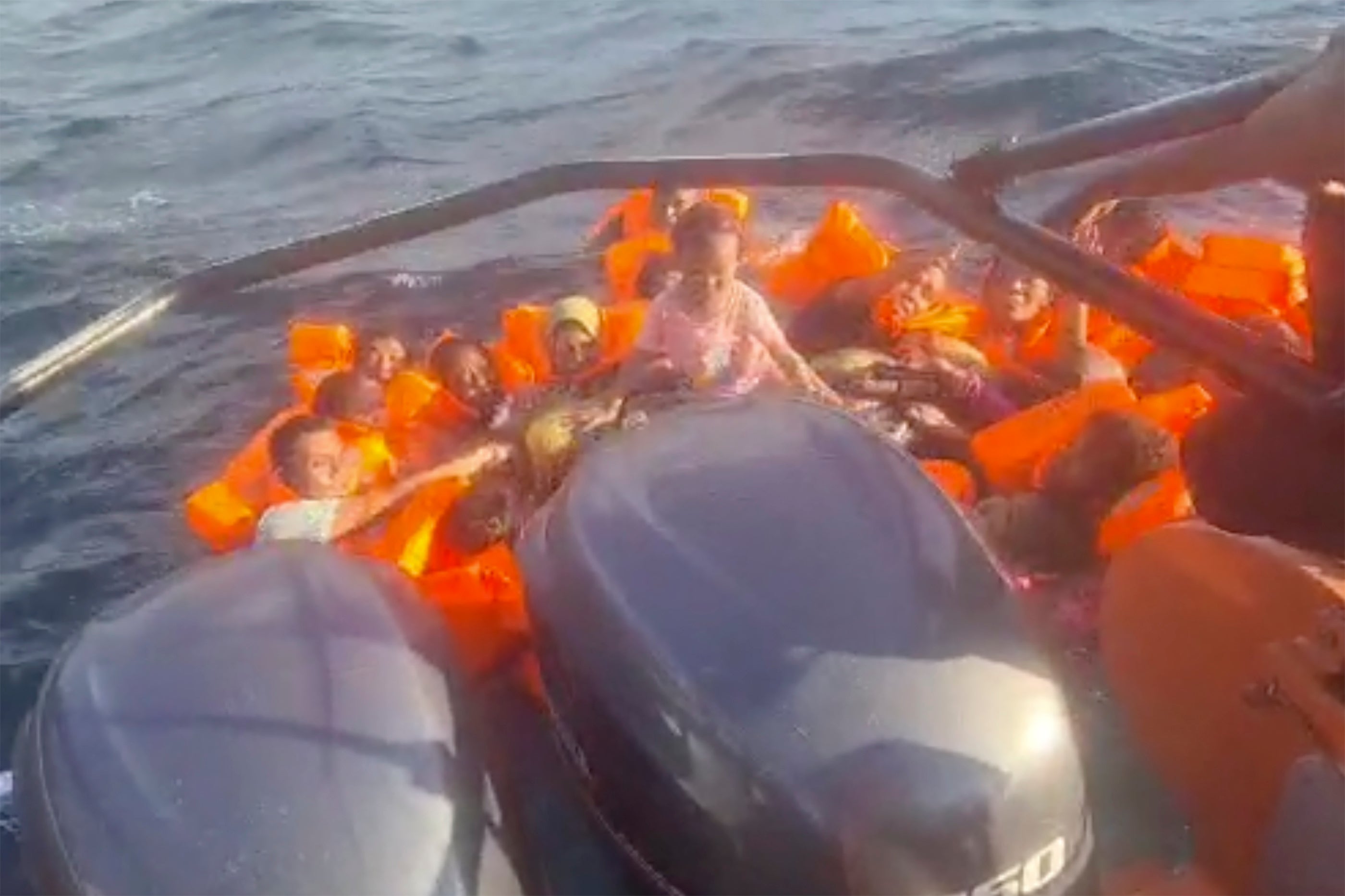 Survivors wearing floatation devices wait to be rescued after their boat caught fire in Naikliu waters off Kupang, Indonesia