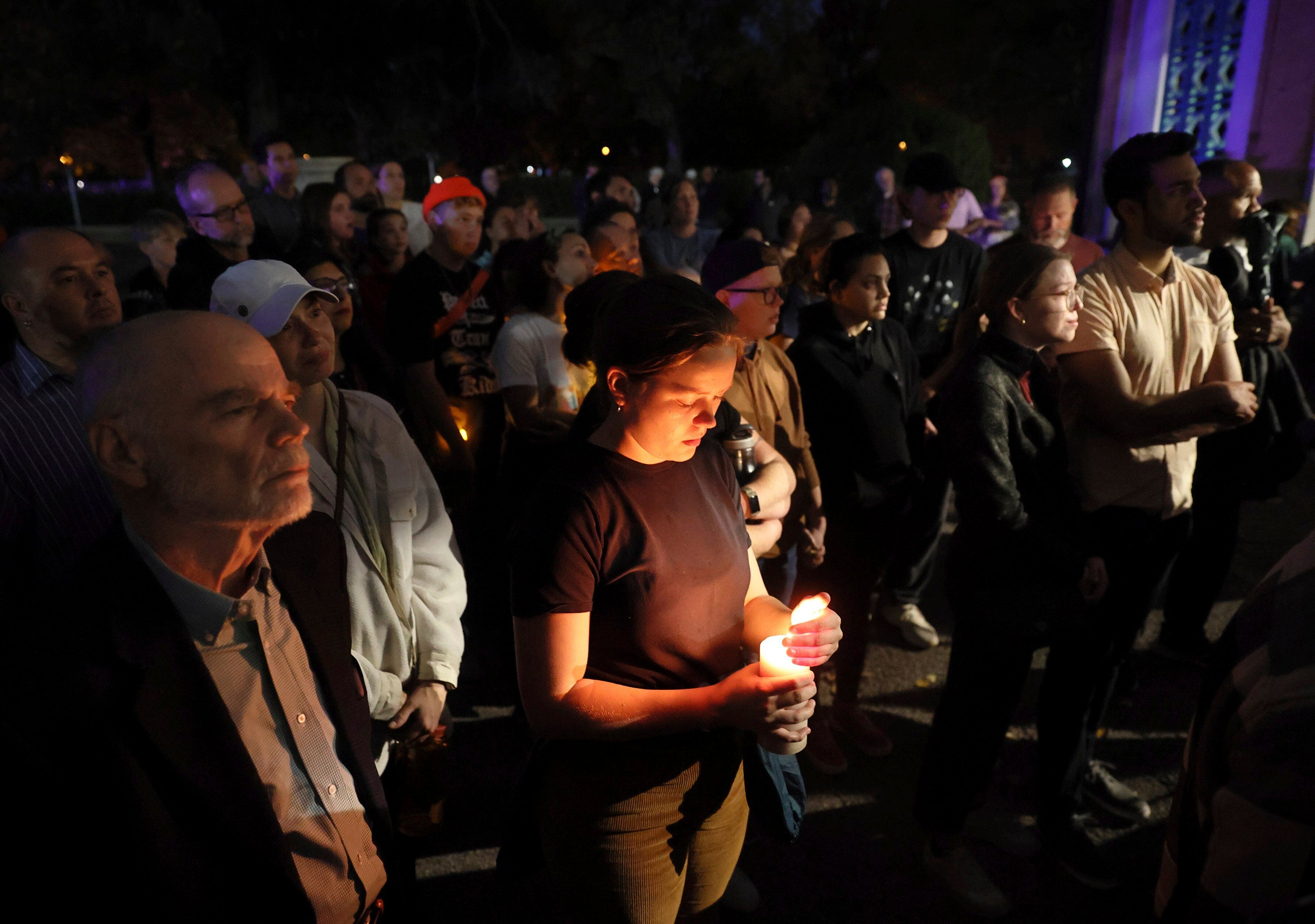 Marie Crane, center, holds a candle during a vigil in Tower Grove Park for the victims of a school shooting at Central Visual & Performing Arts High School in St. Louis on Monday, Oct. 24, 2022