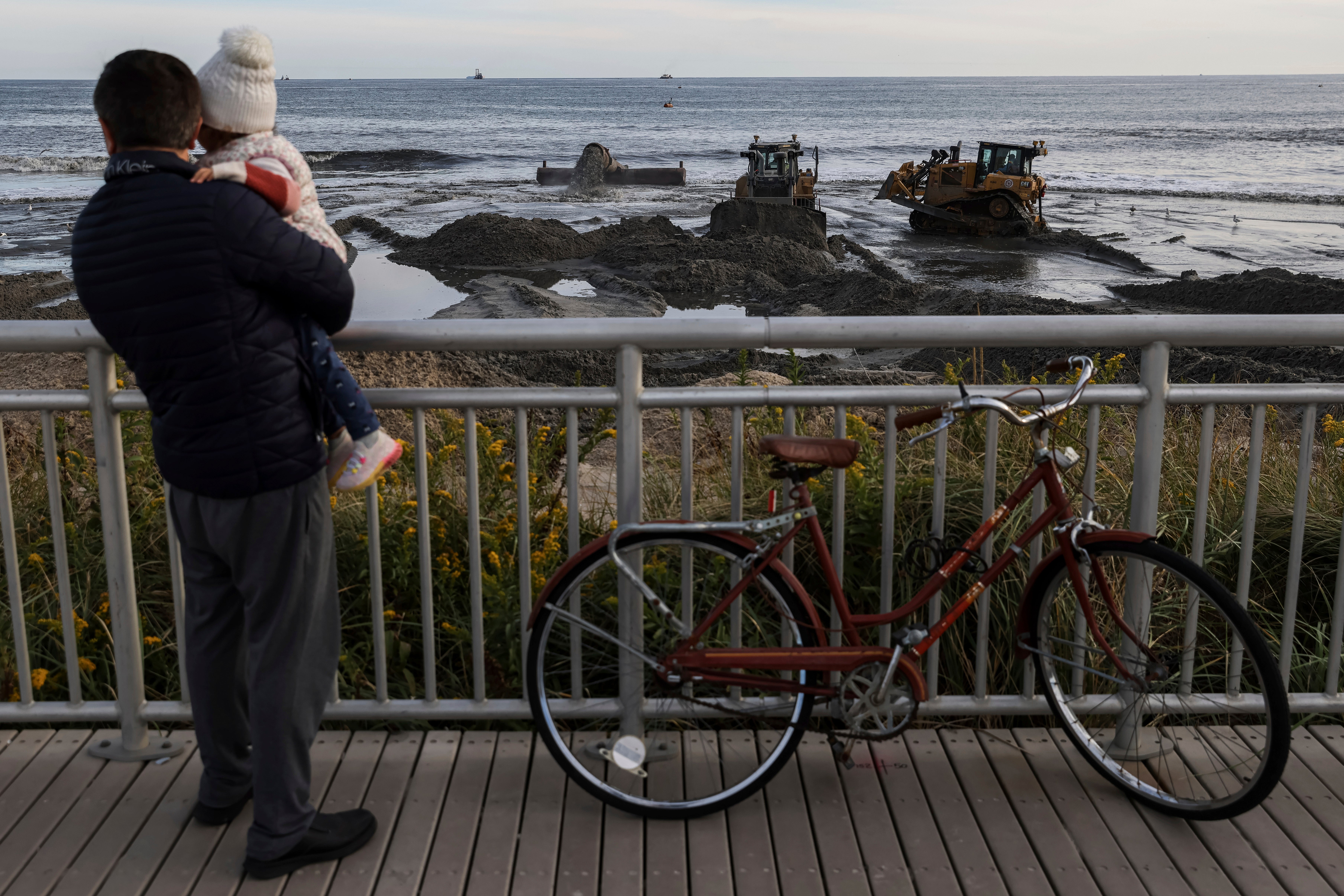 Residents watch sand-dredging work on Saturday, October 22, 2022, in the Far Rockaway neighborhood of Queens. The shorefront resiliency project aims to construct a reinforced dune system designed to block storm surge (AP Photo/Julia Nikhinson)