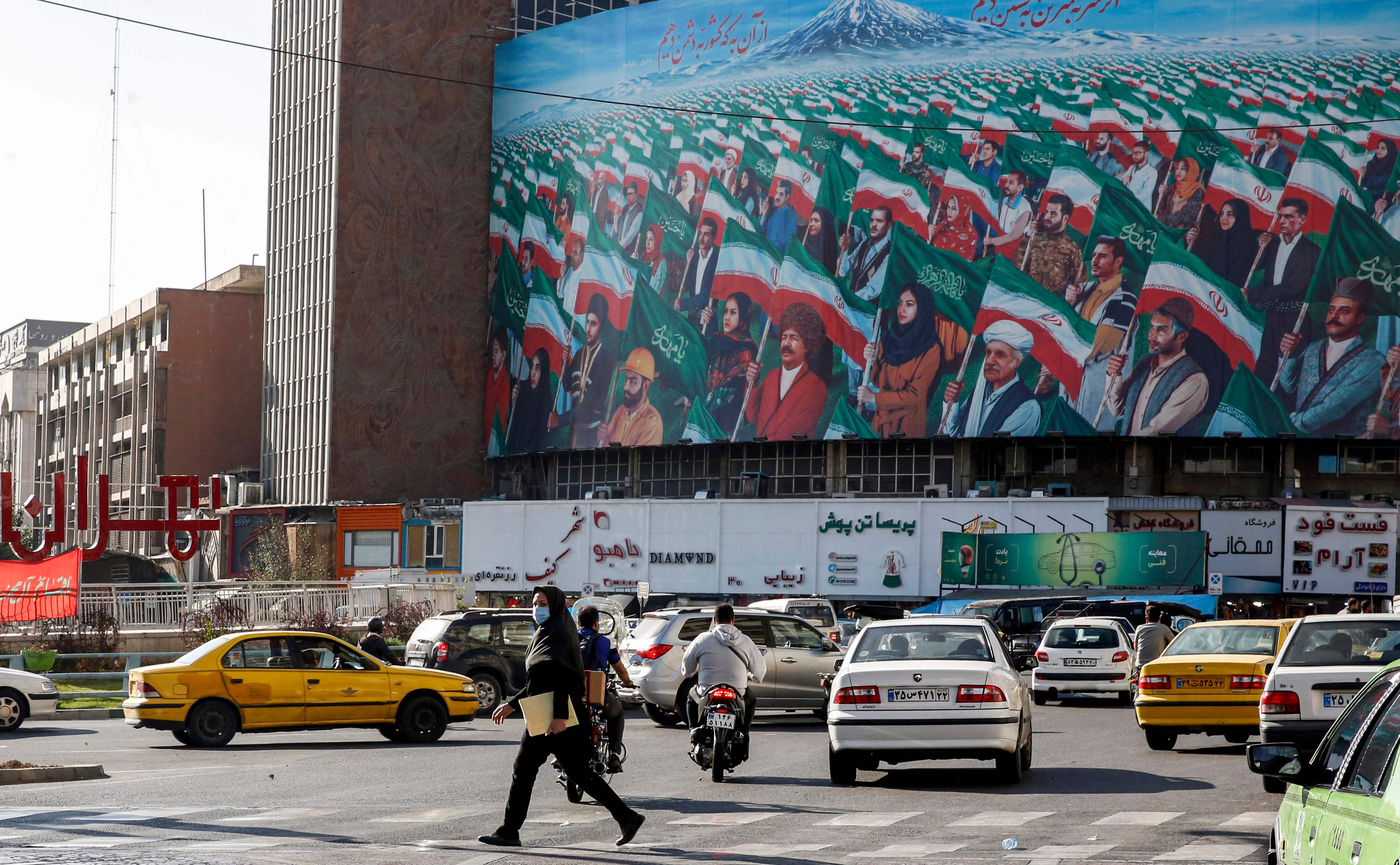 People walk across a pedestrian crossing in Vali Asr square in the centre of Tehran