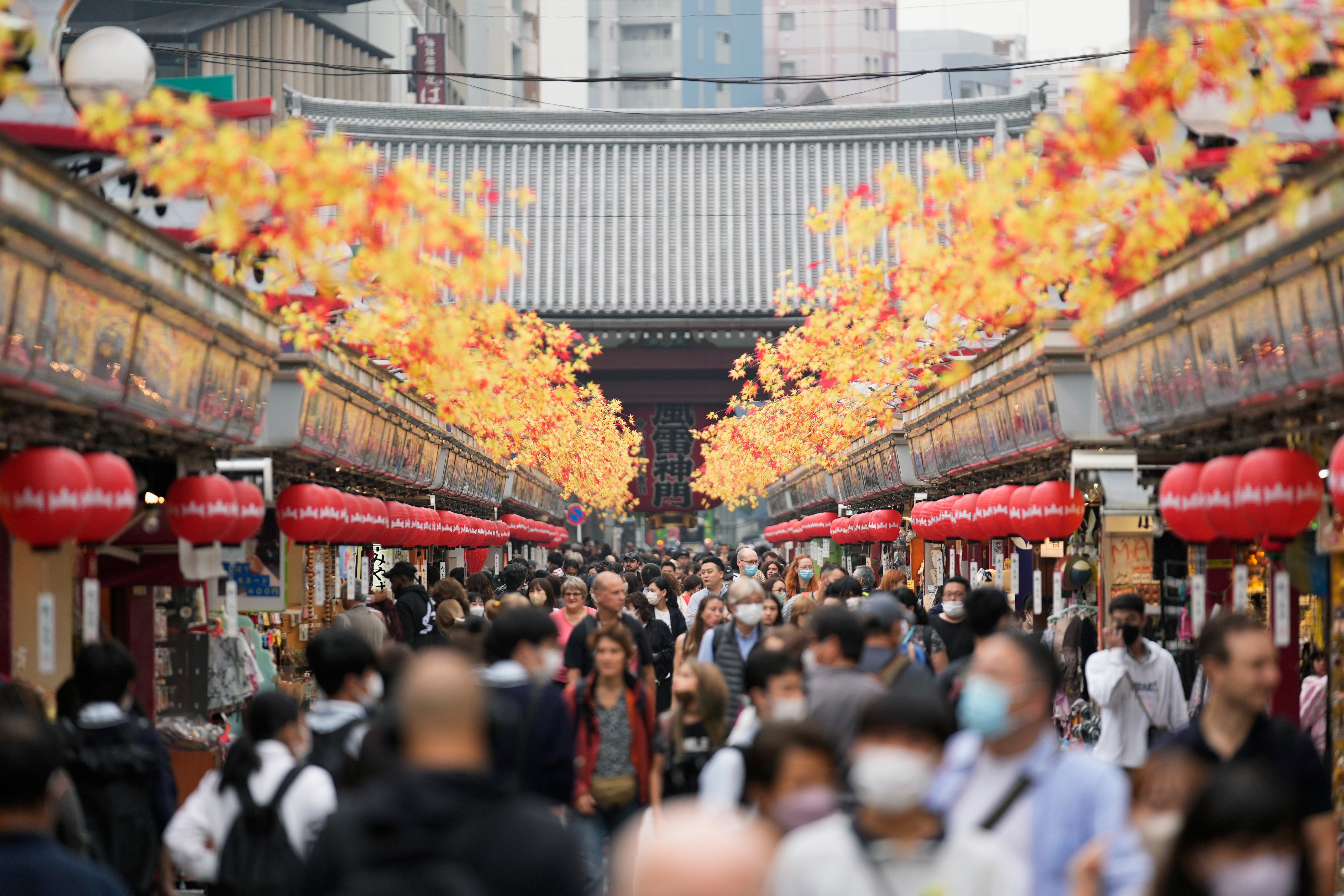 Tourists walk through a promenade lined with souvenir shops leading to the Sensoji Buddhism temple in the famed Asakusa district of Tokyo