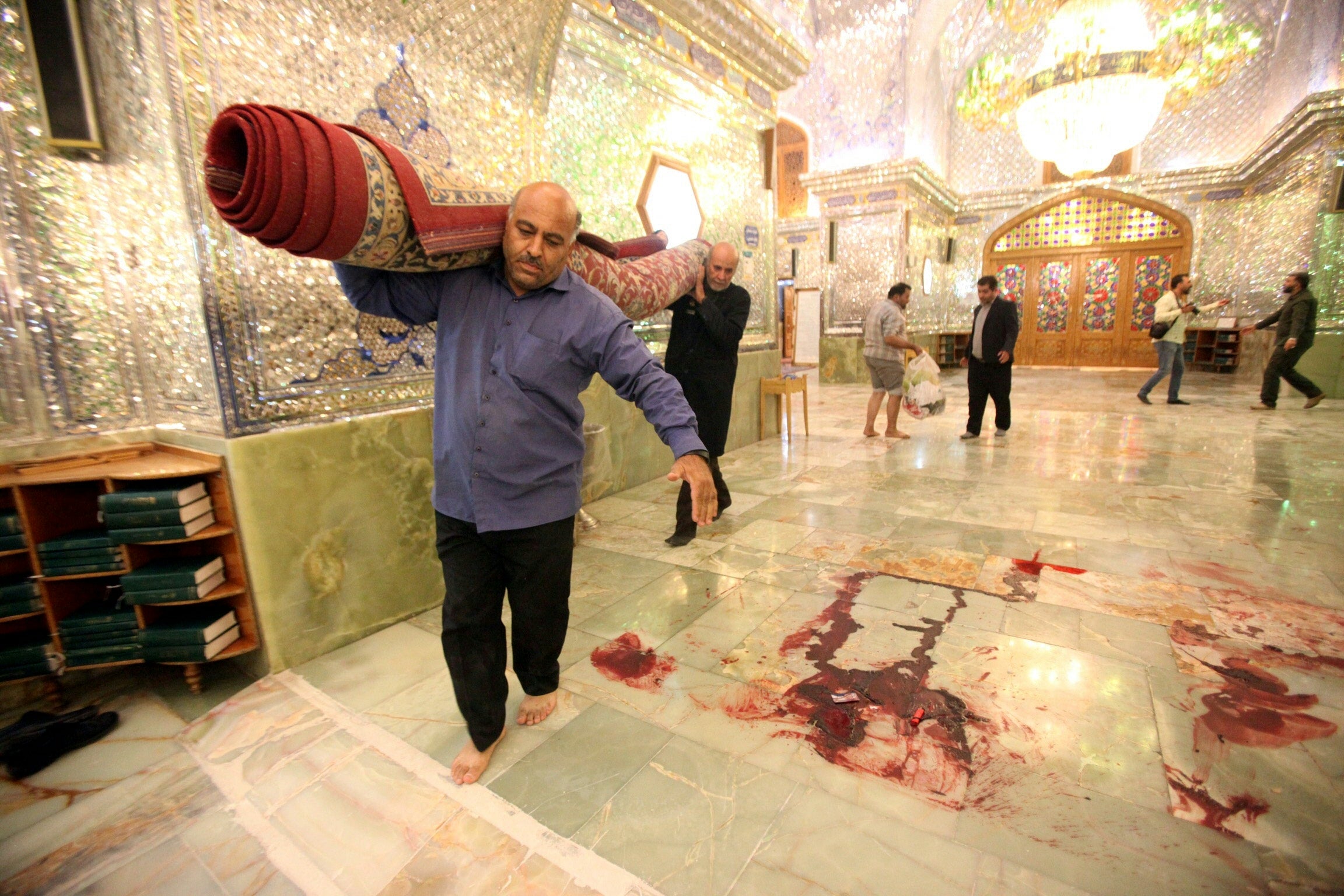 Workers clean up the scene following an armed attack at the Shah Cheragh mausoleum in the Iranian city of Shiraz