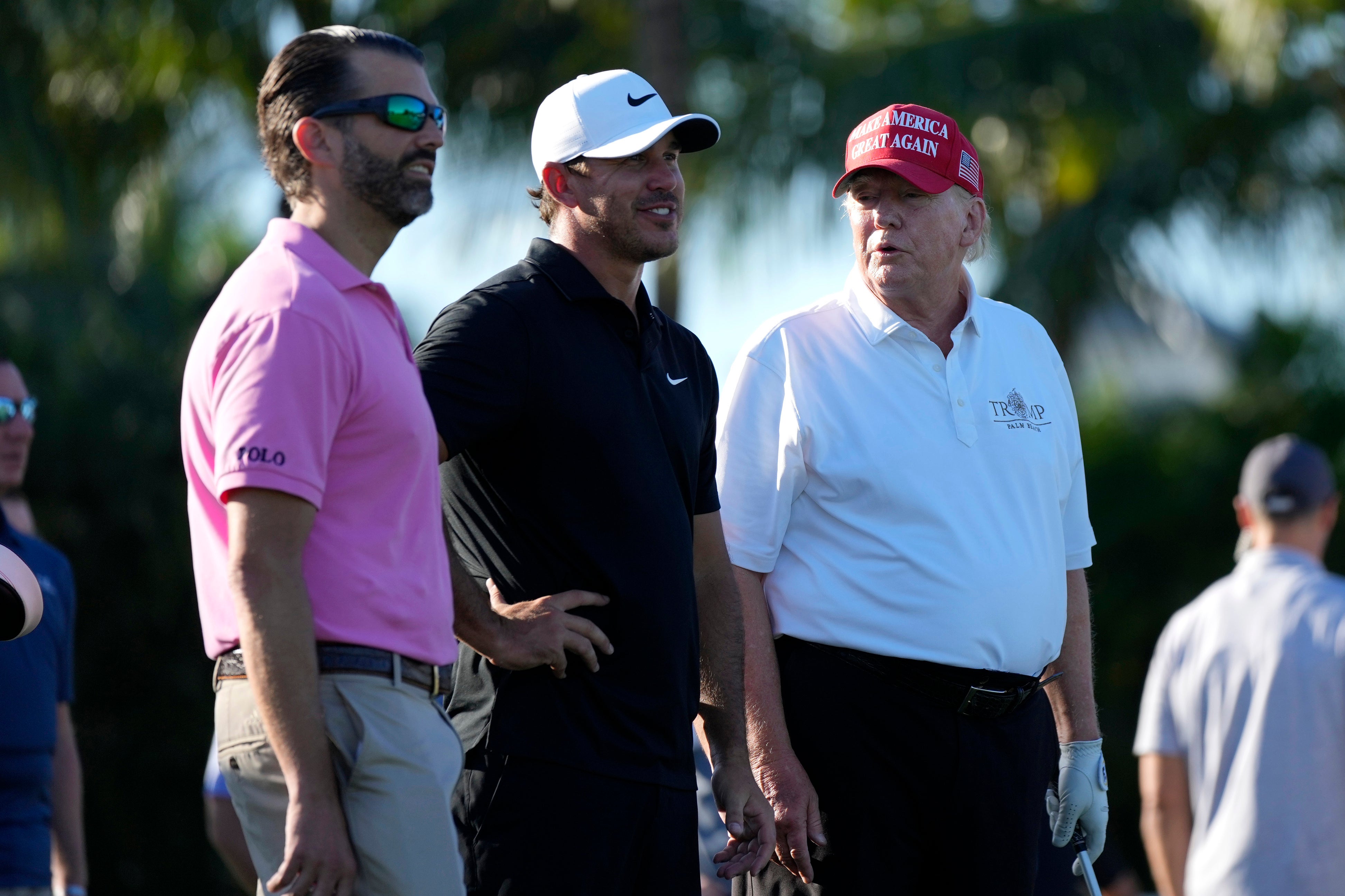 Donald Trump, right, talks with Donald Trump Jr, left, and Brooks Koepka, centre, during the ProAm of the LIV Golf Team Championship at Trump National Doral Golf Club in Florida