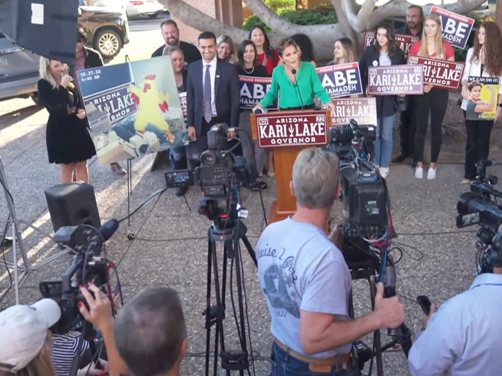 Kari Lake shows a picture of a person in a chicken suit at a press conference