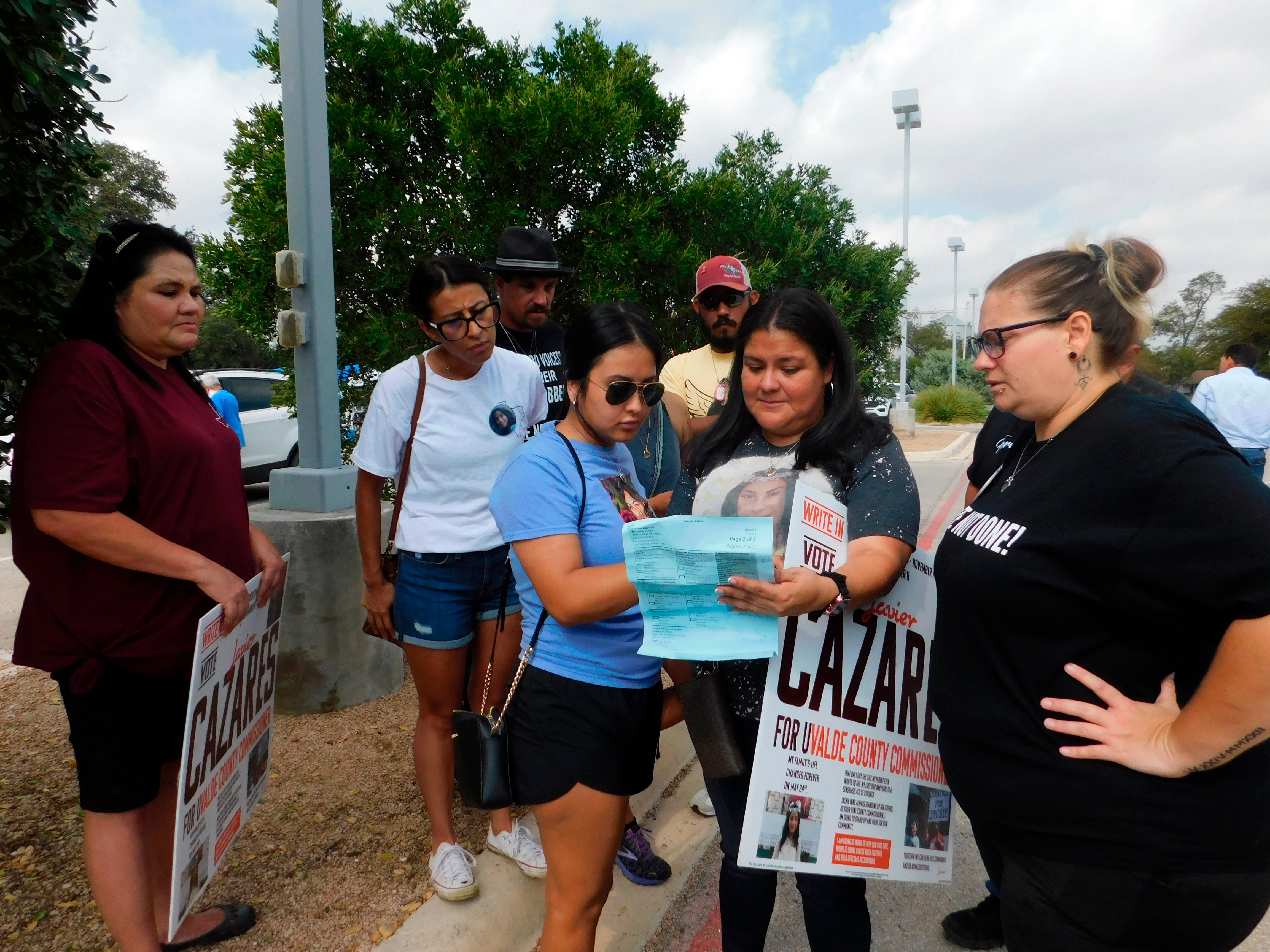 Parents who lost children in the Robb Elementary School shooting look at a sample ballot before going to vote on Monday