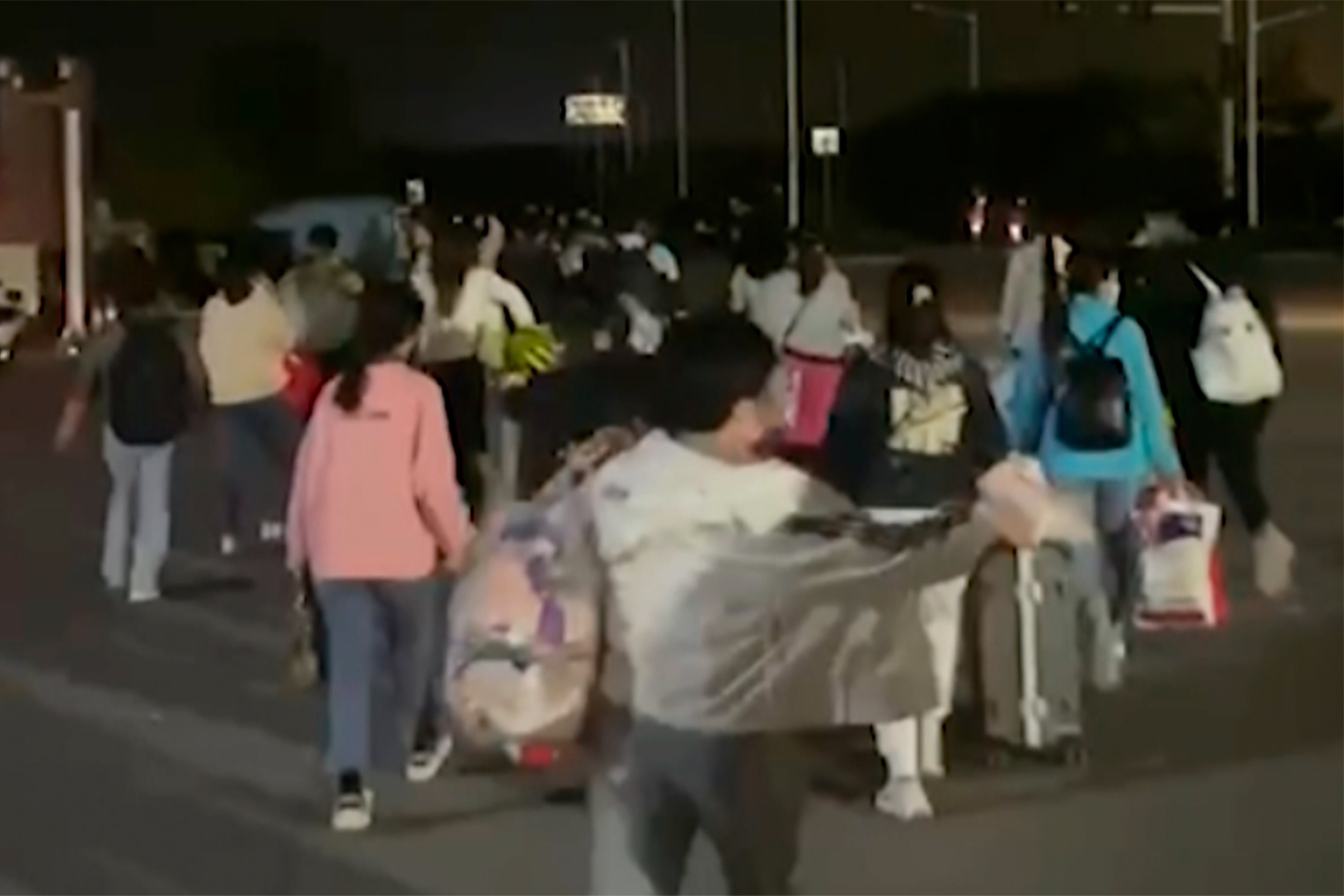 People with suitcases and bags are seen leaving the Foxconn compound in Zhengzhou