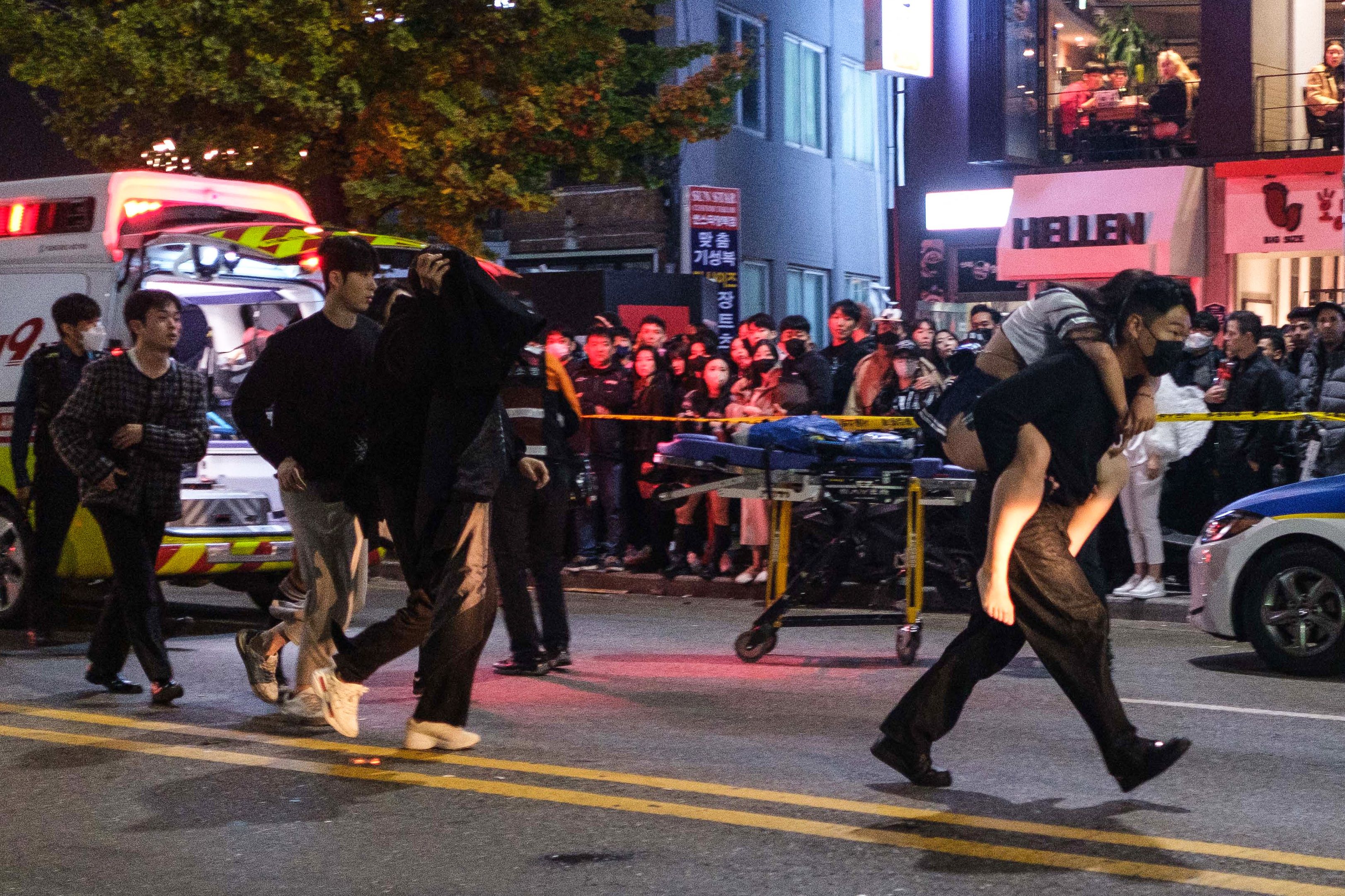 A man carries a woman, who was injured in a Halloween stampede, toward an ambulance