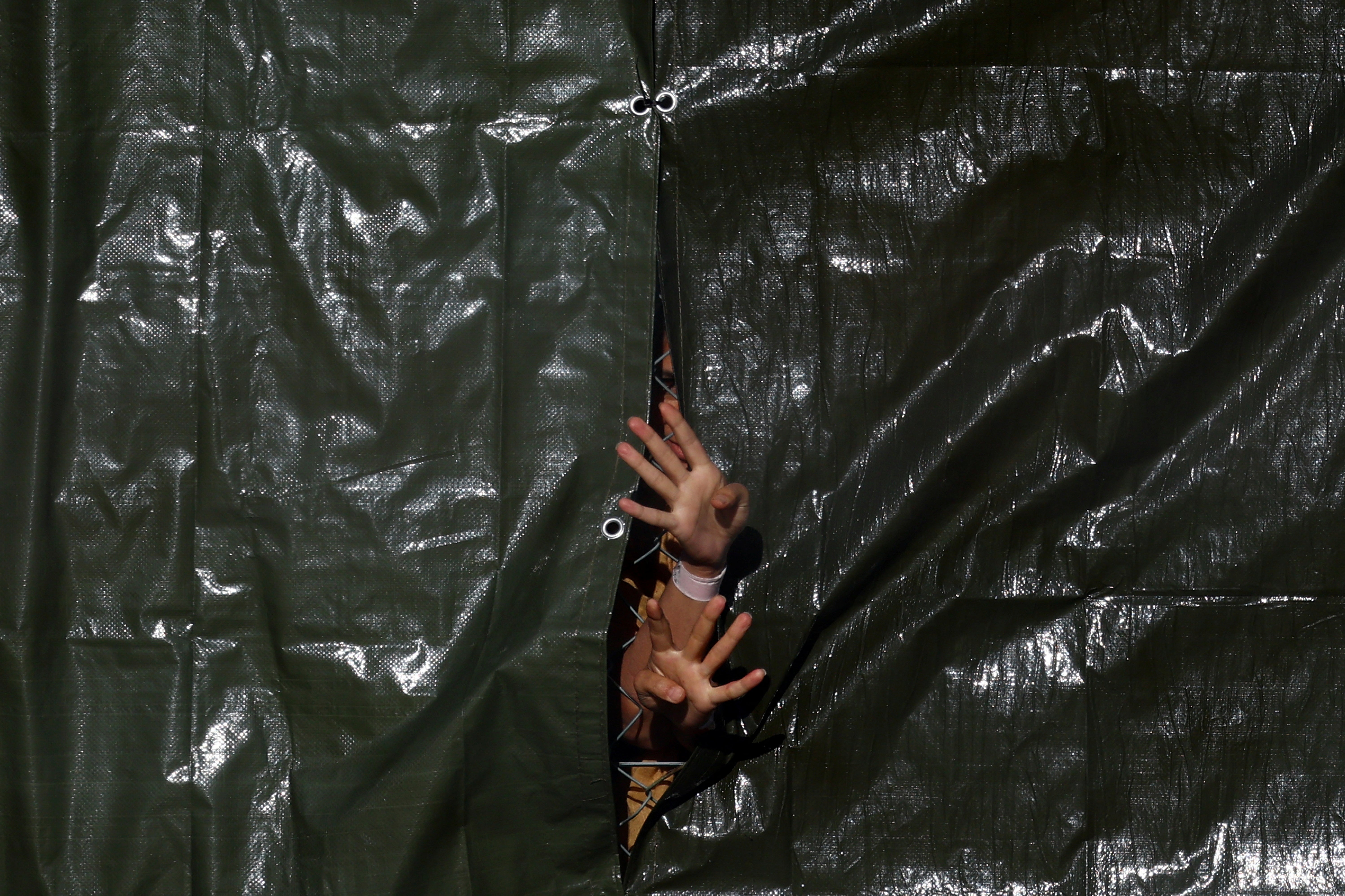 Detainees gesture through a fence at an immigration processing centre in Manston