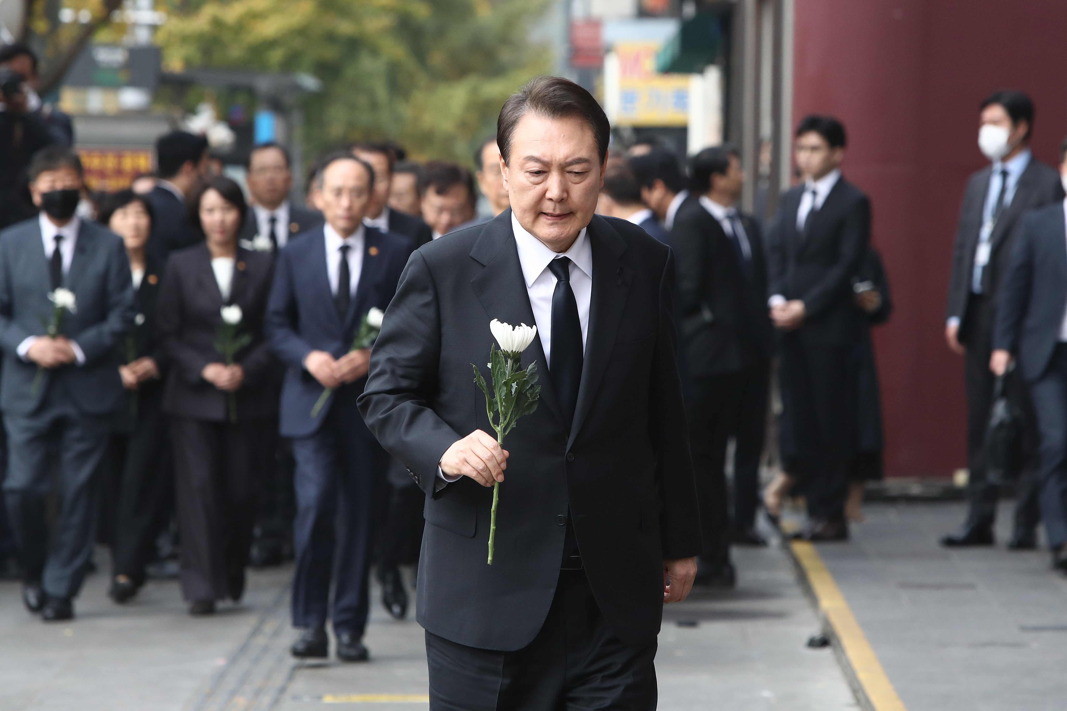 South Korean president Yoon Suk-yeol holds a flower for the victims of the Halloween celebration stampede, on the street near the scene on 1 November 2022 in Seoul, South Korea