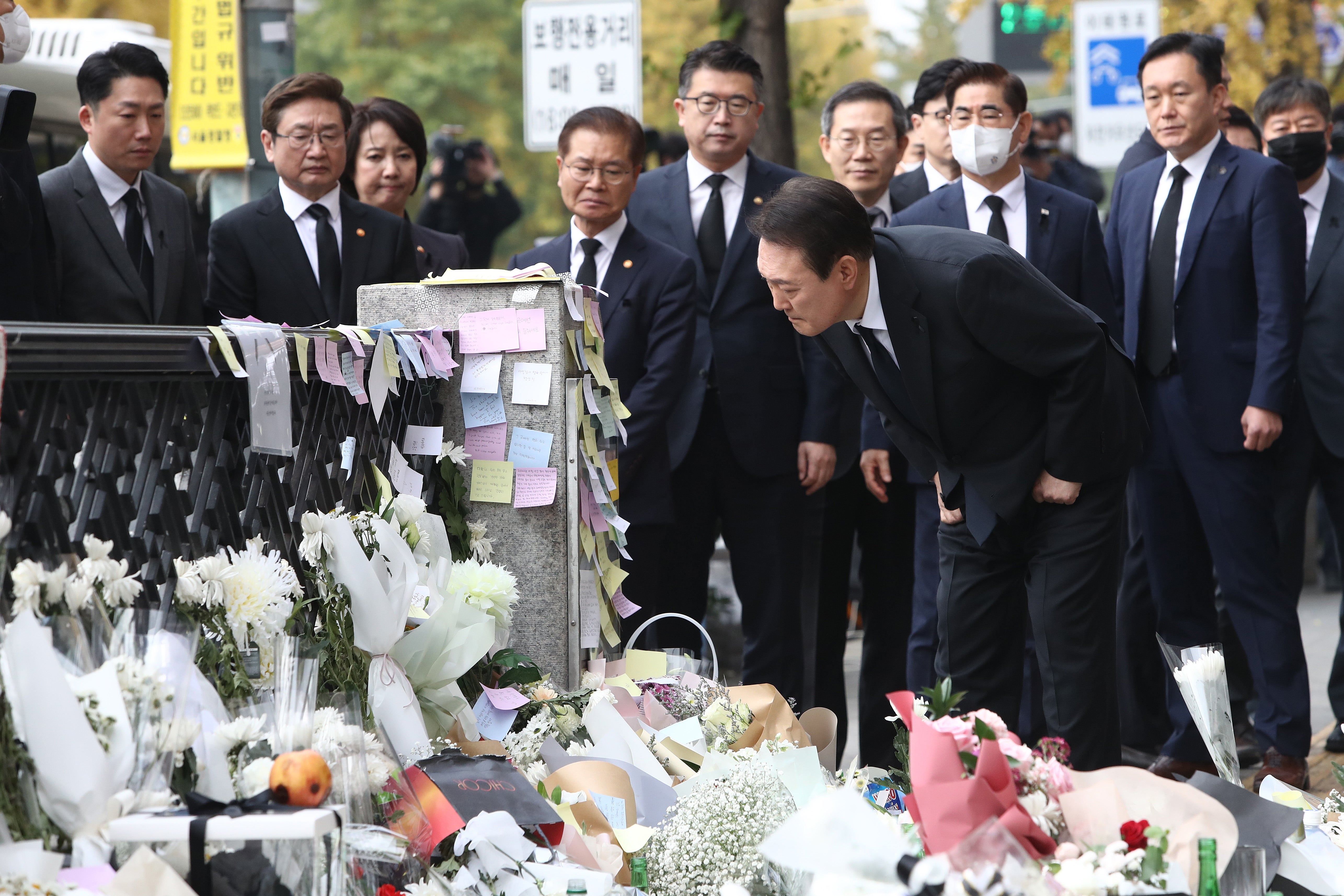 South Korean president Yoon Suk-yeol reads messages written by mourners while paying tribute to the victims of the Halloween celebration stampede, on the street near the scene on 1 November 2022 in Seoul, South Korea