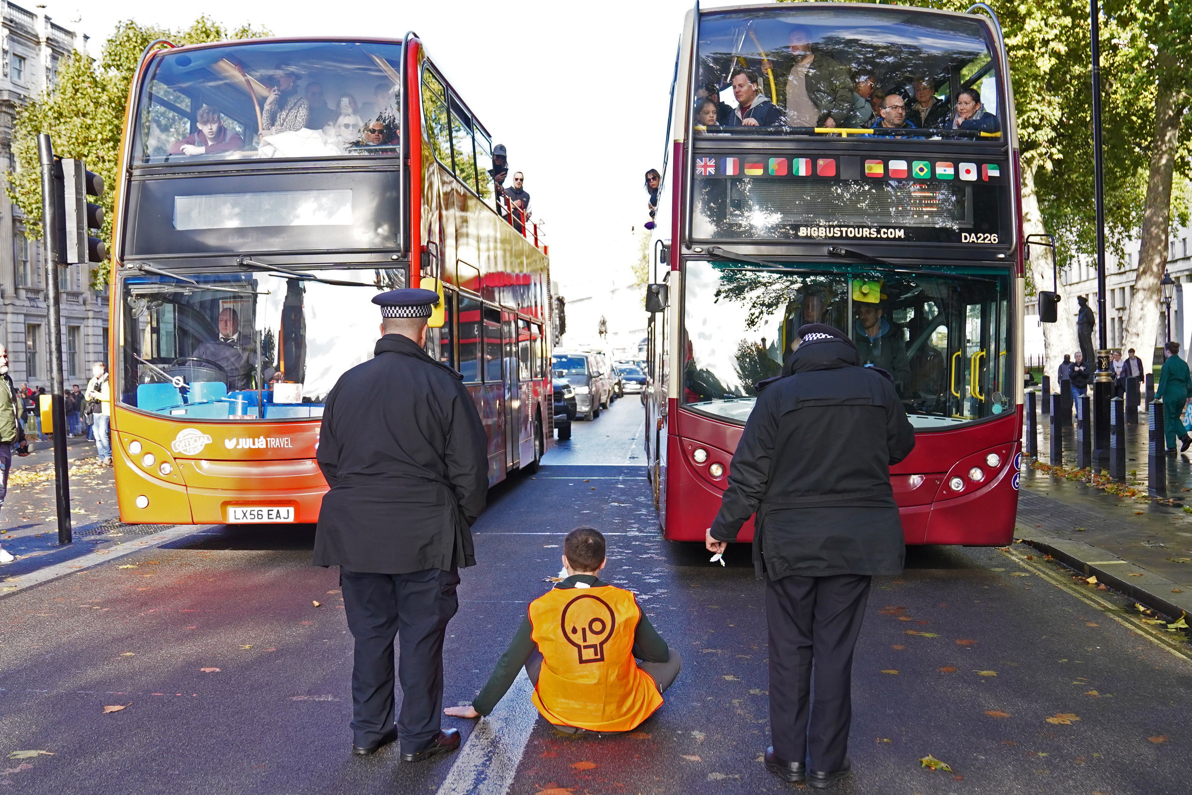 A Just Stop Oil activist sits in the middle of Whitehall in Westminster