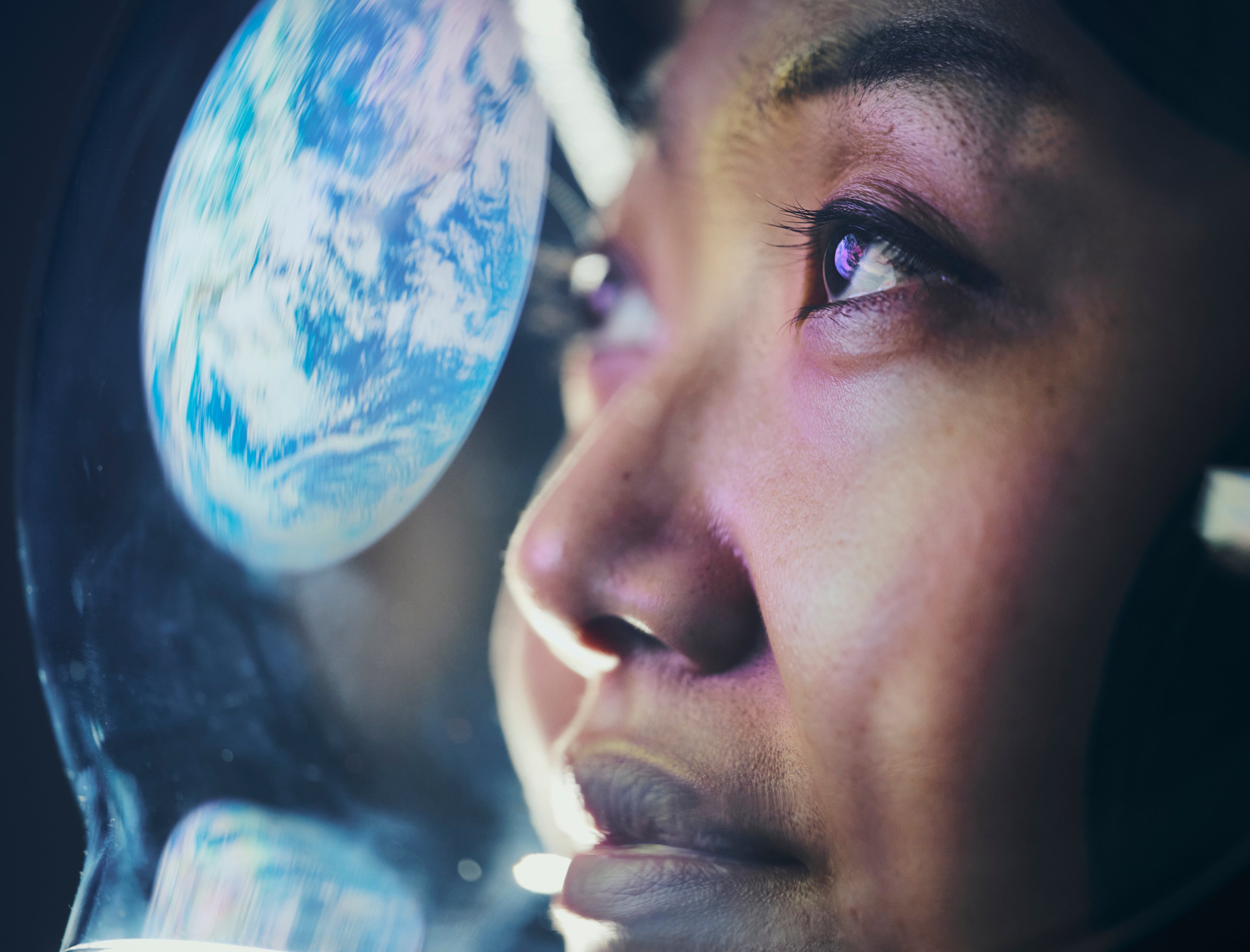 A woman wearing a helmet looking at Earth from space. (Earth image provided by NASA)