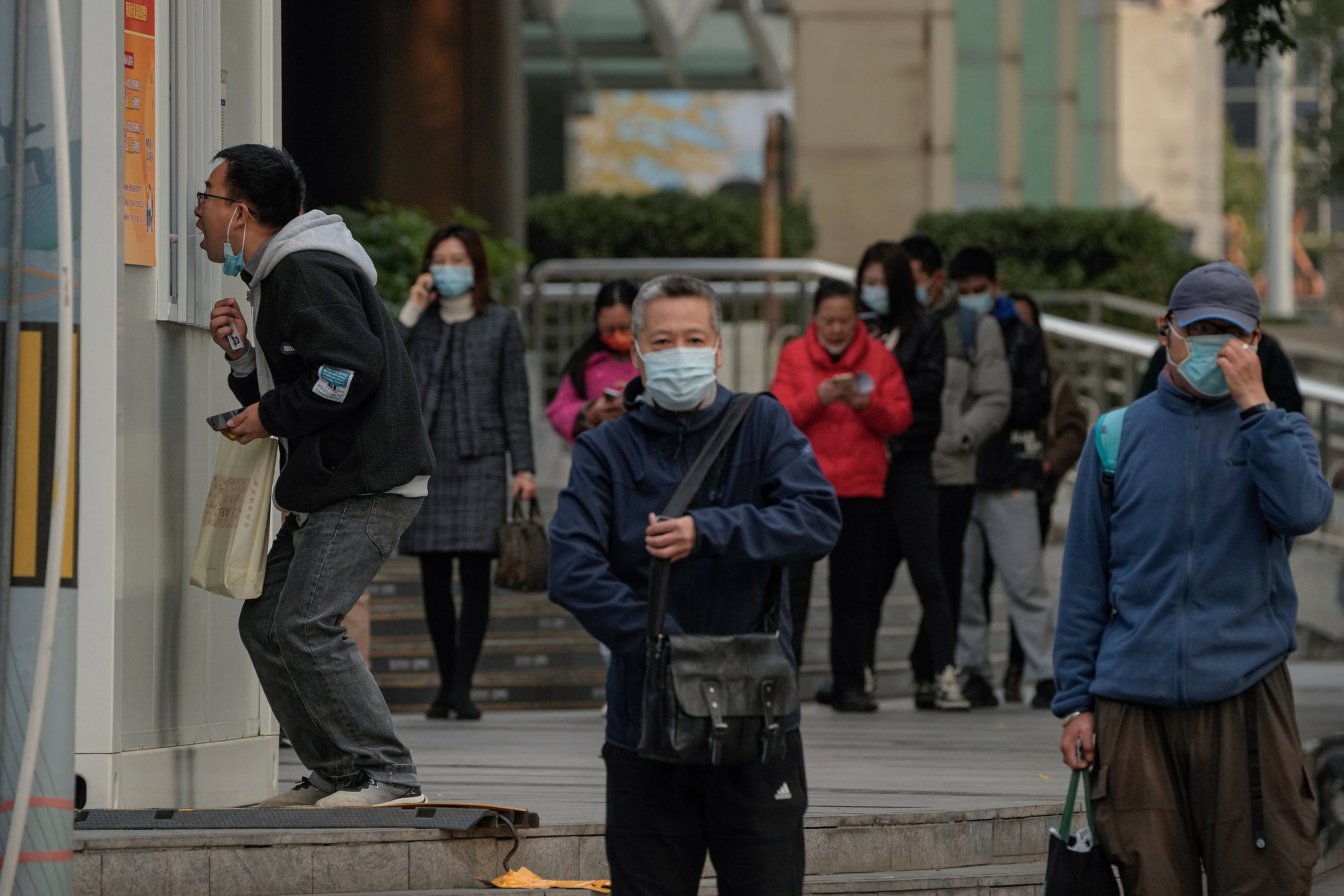 Residents line up to get their routine COVID-19 throat swabs at a coronavirus testing site setup along a pedestrian walkway in Beijing