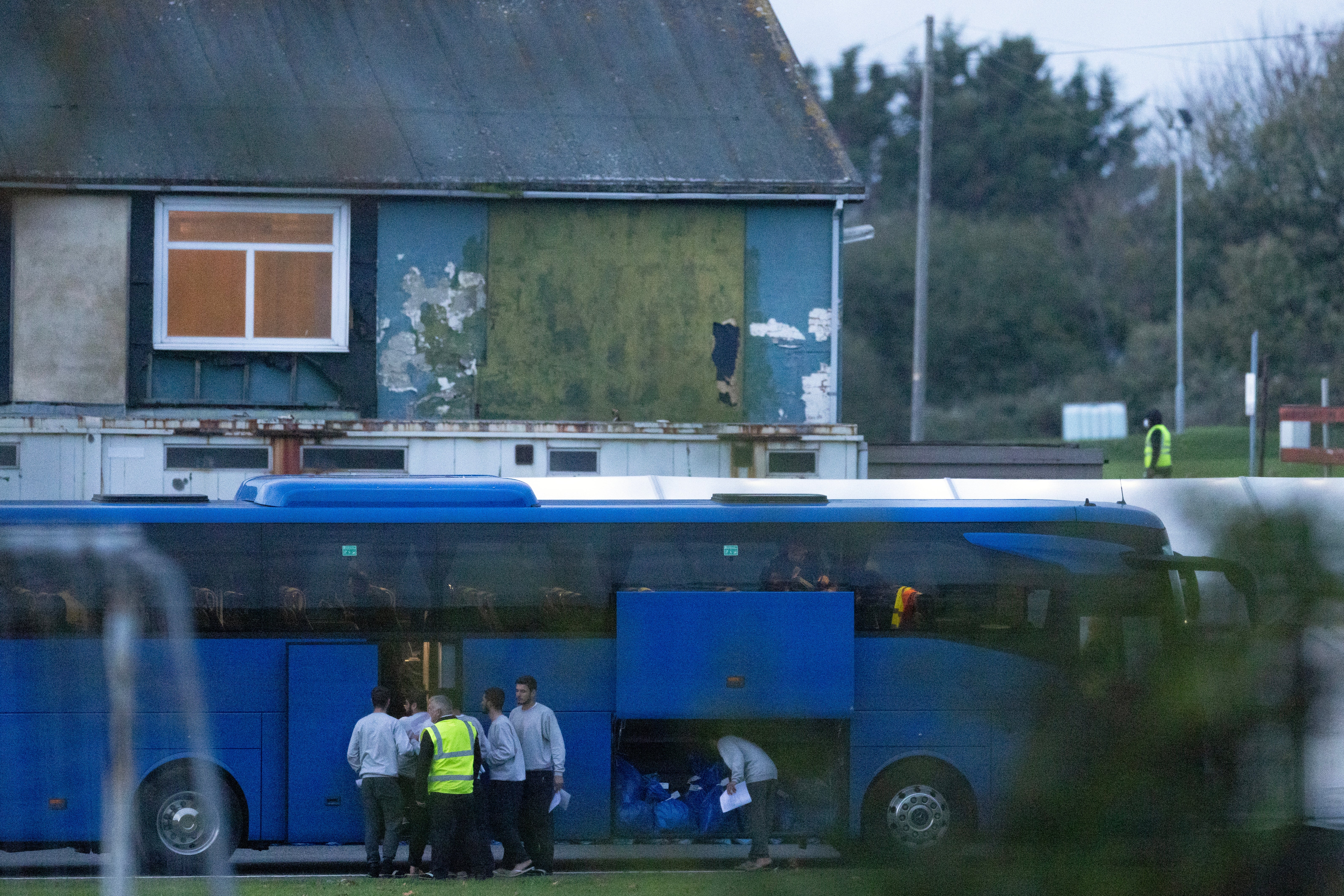 Migrants board a bus to leave a holding facility at Manston Airfield on 2 November