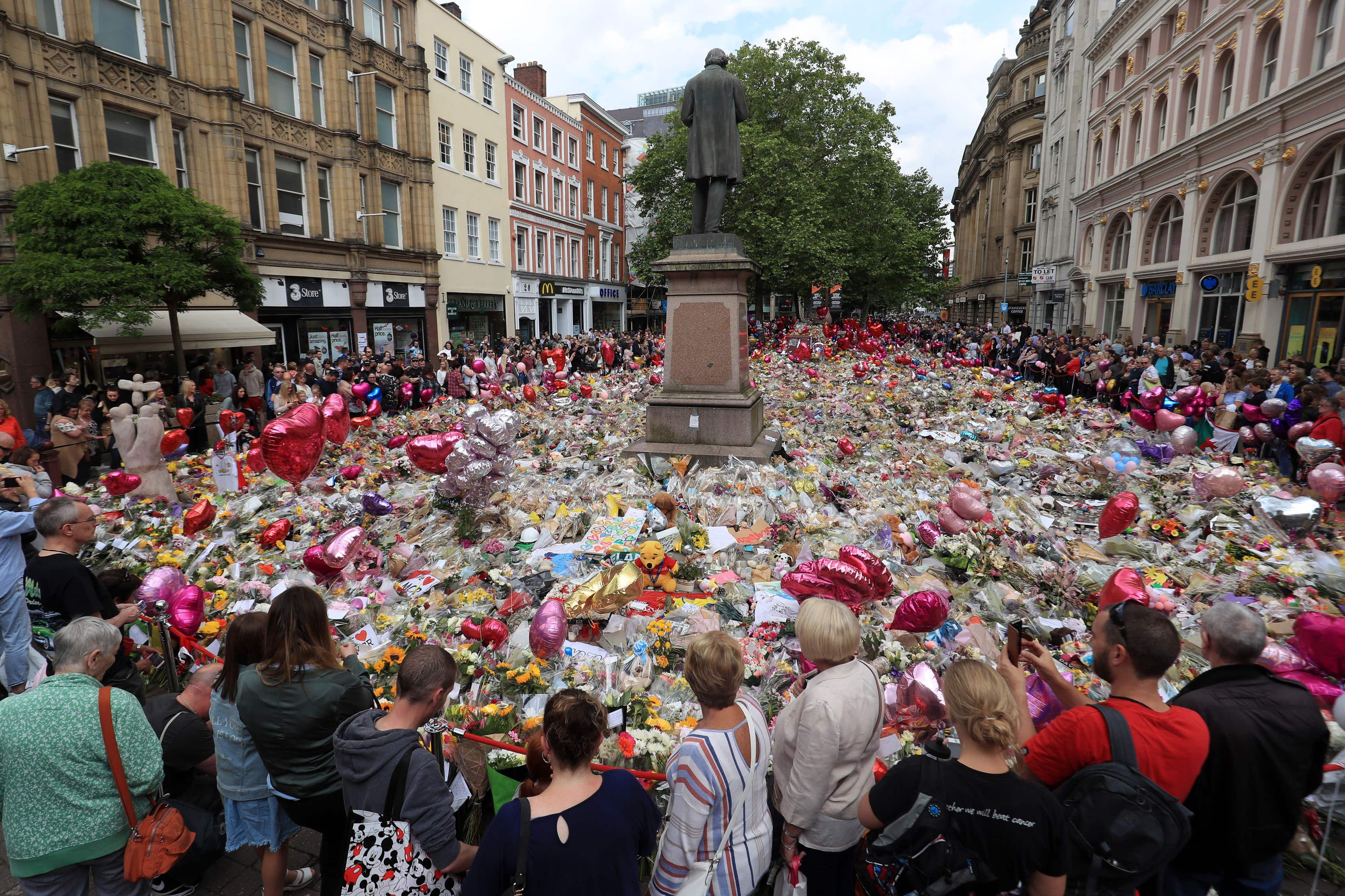 People look at flowers and tributes left in St Ann’s Square in Manchester following the Manchester Arena terror attack