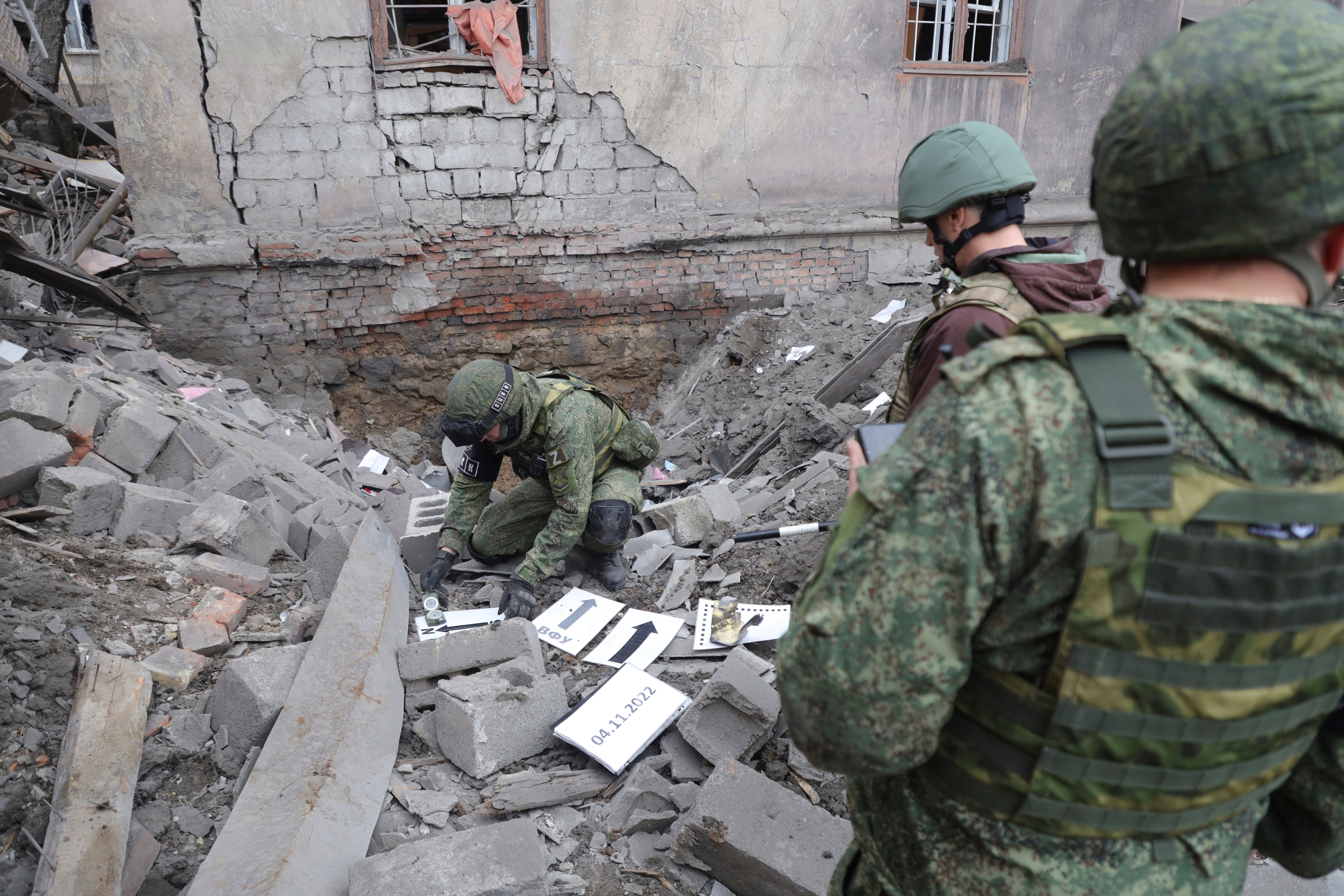 Investigators inspect a site of an apartment building after shelling by Ukrainian forces in Makiivka, Donetsk People's Republic,