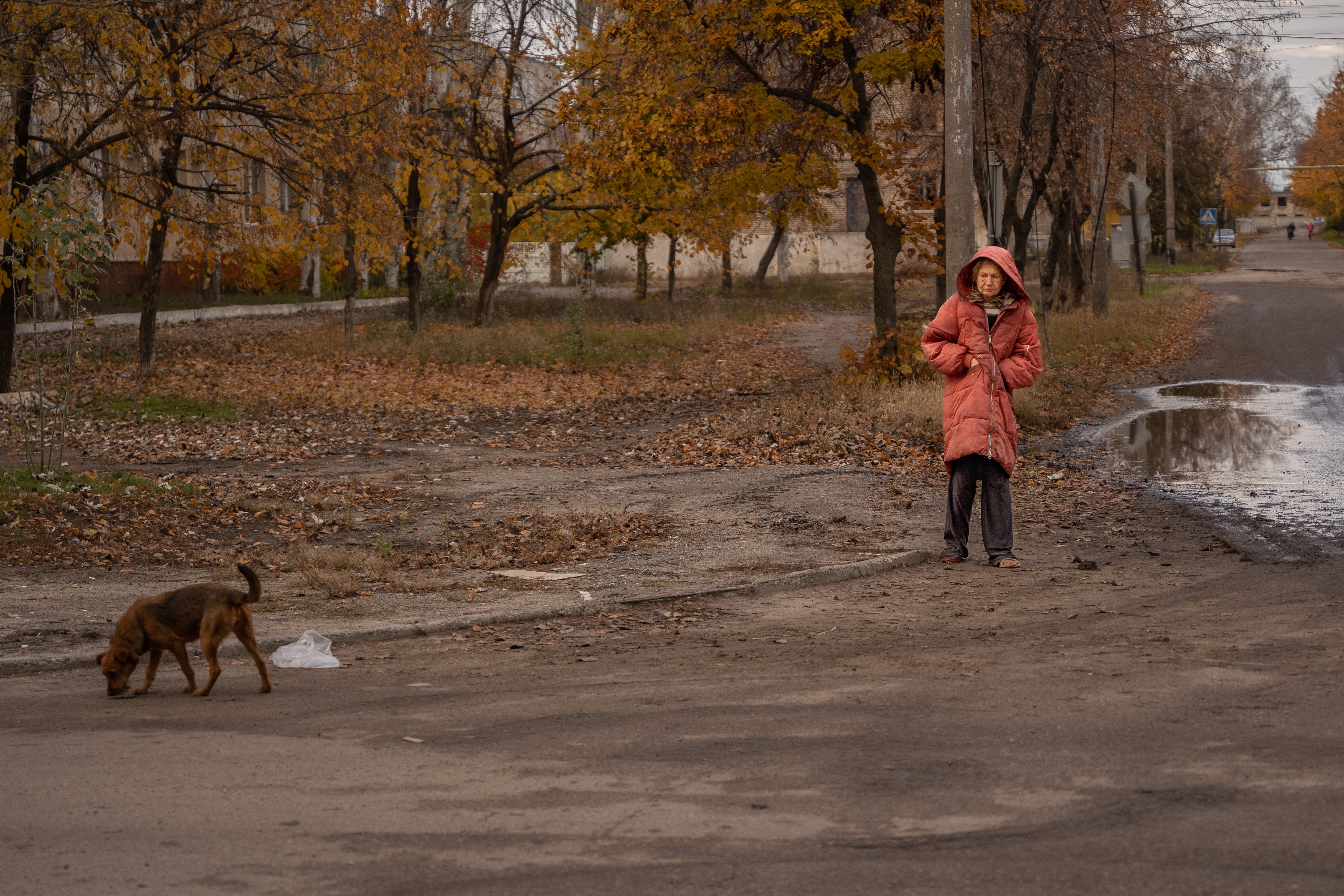 An elderly woman, partially barefoot, walks through Lyman to get food