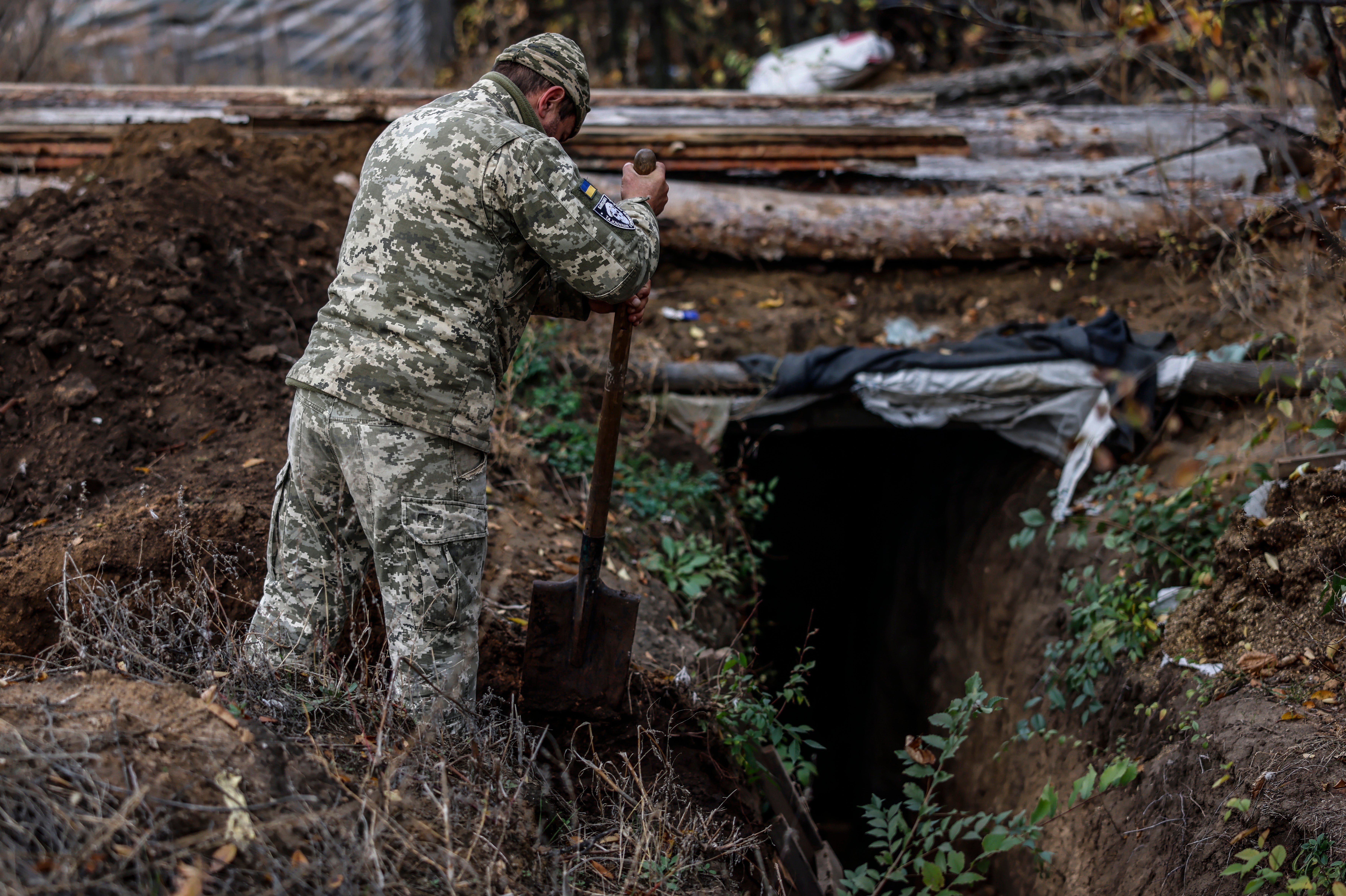 A Ukrainian soldier digs a trench by the dugout in the Kherson region