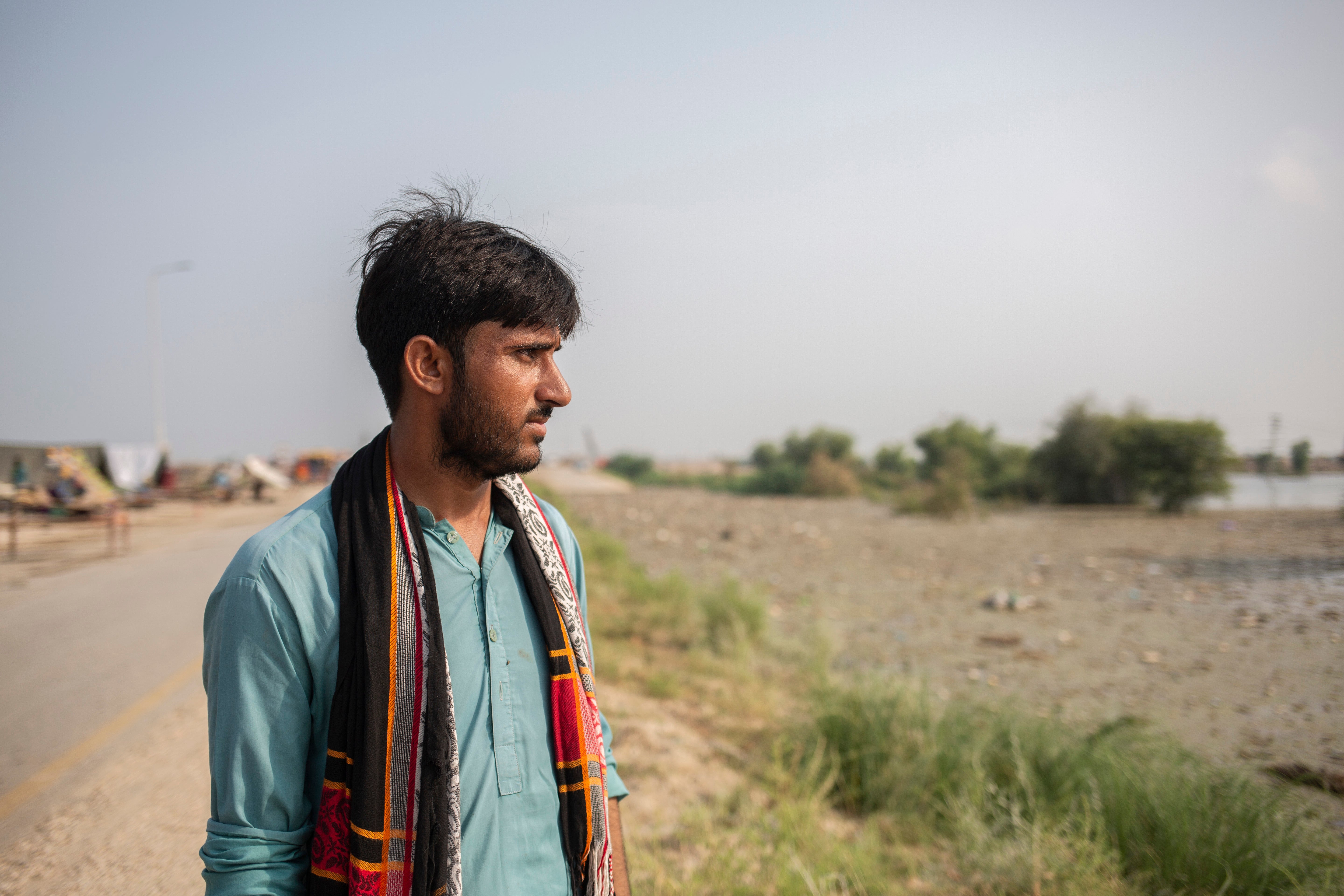 Mazhar Hussain Birhamni, a student, looks at his house which is submerged in water