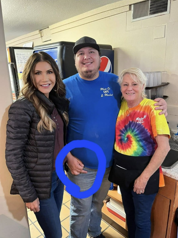 Gov Kristi Noem, left, poses for a picture with a constituent, right, and Stefen Monteau, middle, who was later terminated from his job